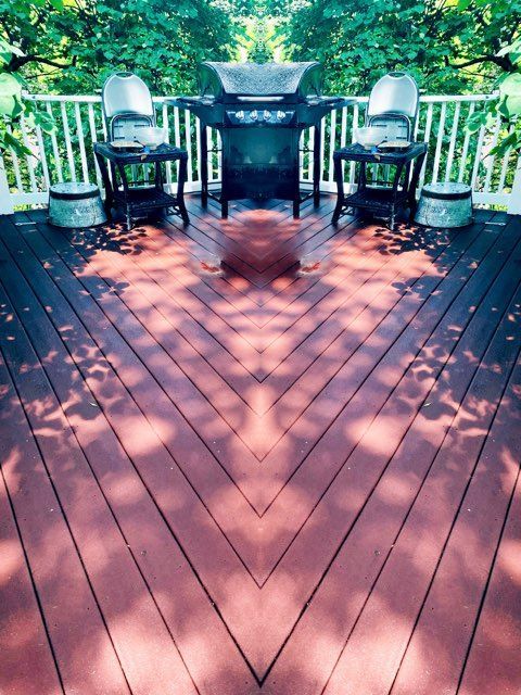 Deck construction in progress; a person works on the railing. White siding, concrete, and wooden supports visible.