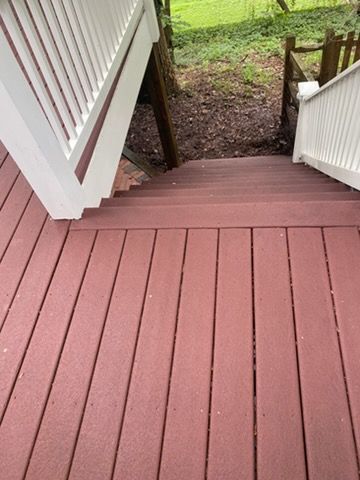 White deck with railing attached to a light blue house, overlooking green grass.