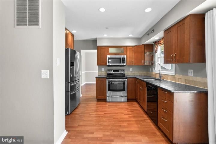 Modern kitchen with stainless steel appliances, wood cabinets, and hardwood floors
