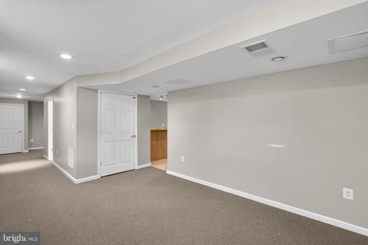 Empty carpeted room with gray walls, white trim, and open doorways in a house interior