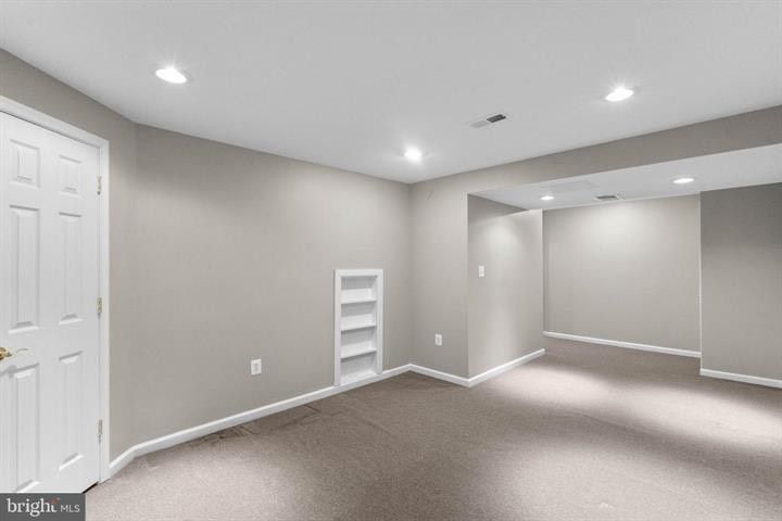 Empty gray bedroom with carpet, white trim, closet doors, and recessed lighting