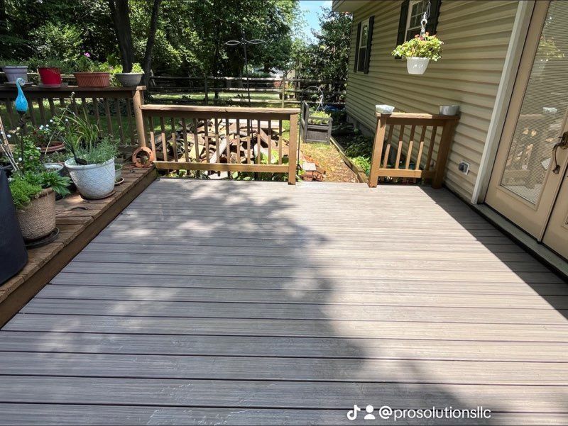 White deck with railing, stairs, and gray decking in backyard with grass and white fence.