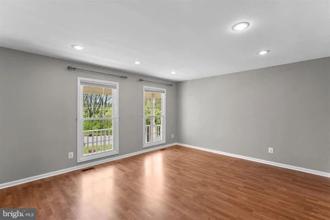 Newly refinished wood floor in a room with a brick fireplace and light beige walls.
