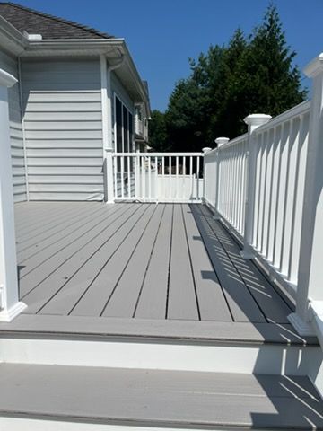 White wooden deck with railing beside a house on a sunny day
