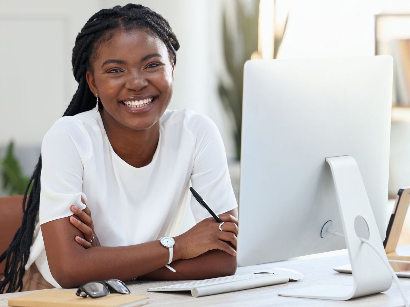A woman is smiling while sitting at a desk in front of a computer