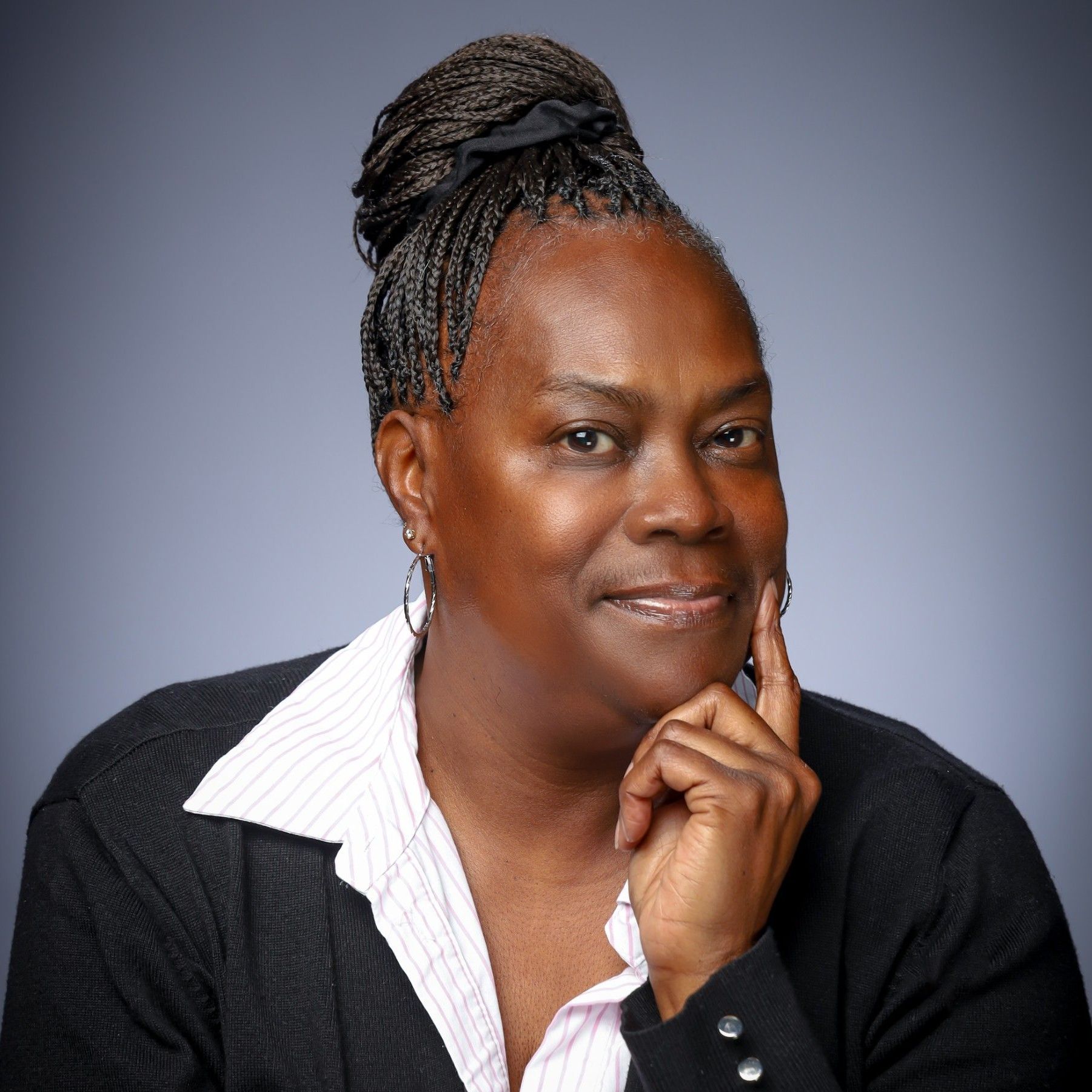 A woman wearing glasses and a suit is smiling.