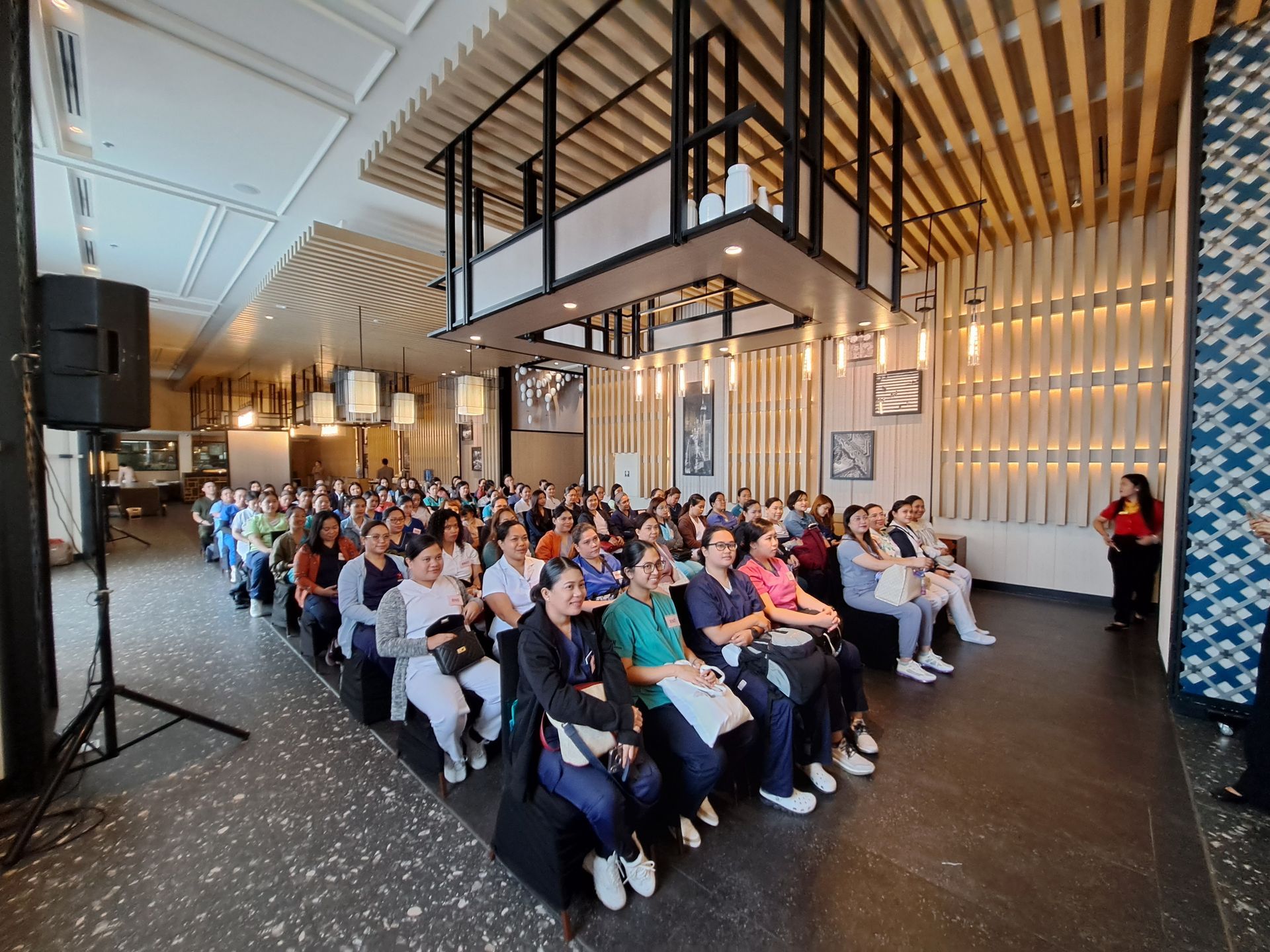 A large group of people are sitting in a room watching a presentation.