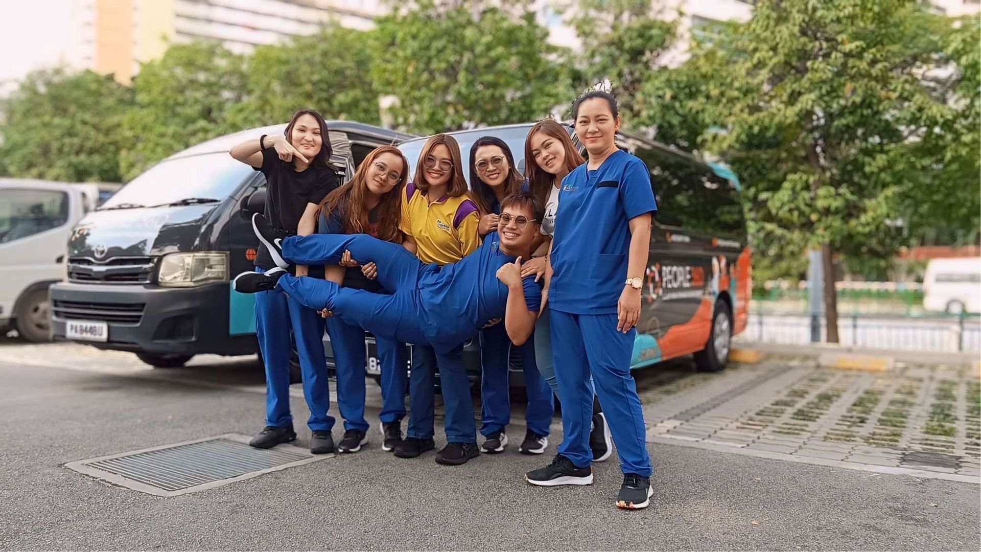 A group of Filipino nurses in Singapore are posing for a picture in front of a van.