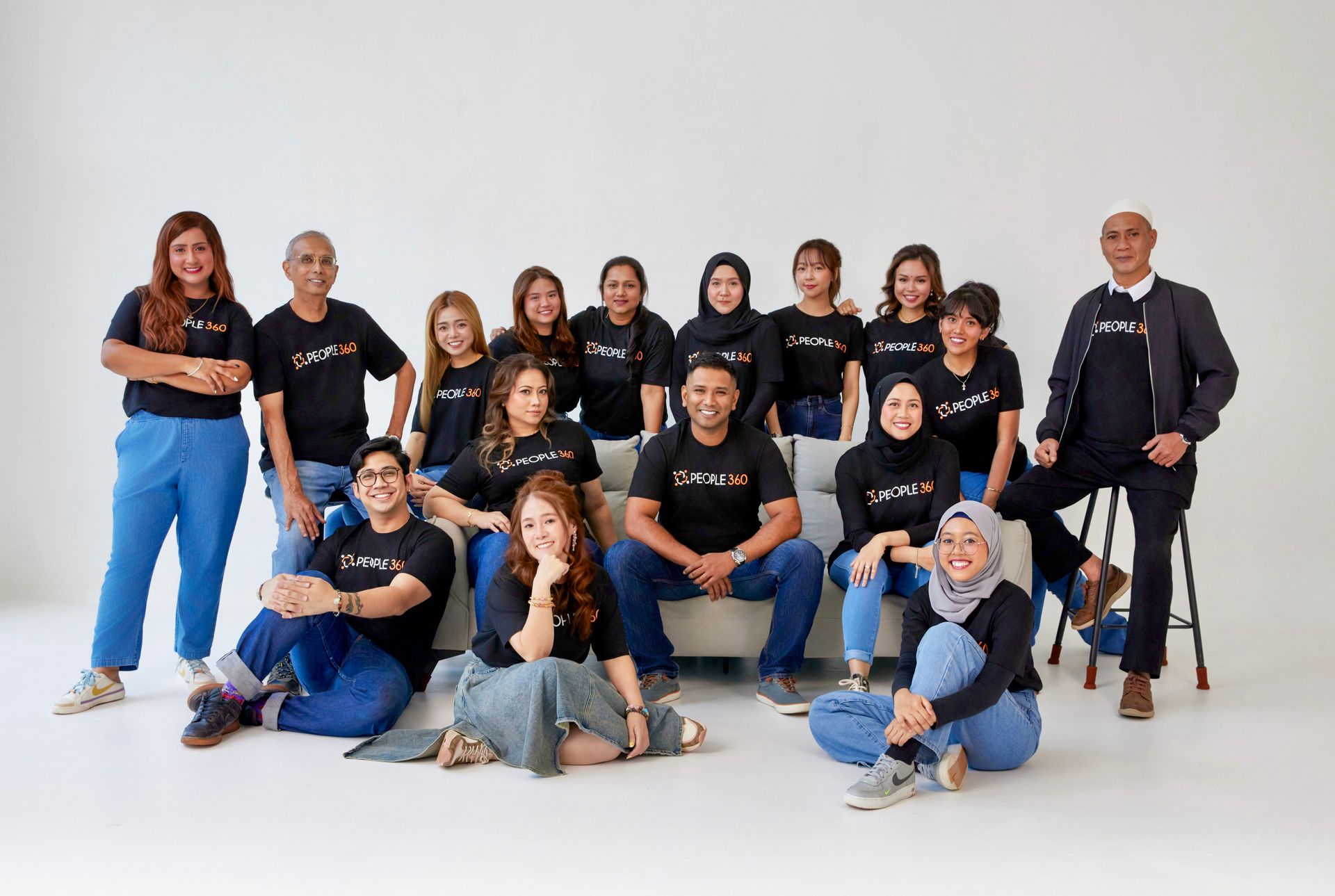 A group of people are posing for a picture while sitting on a couch.