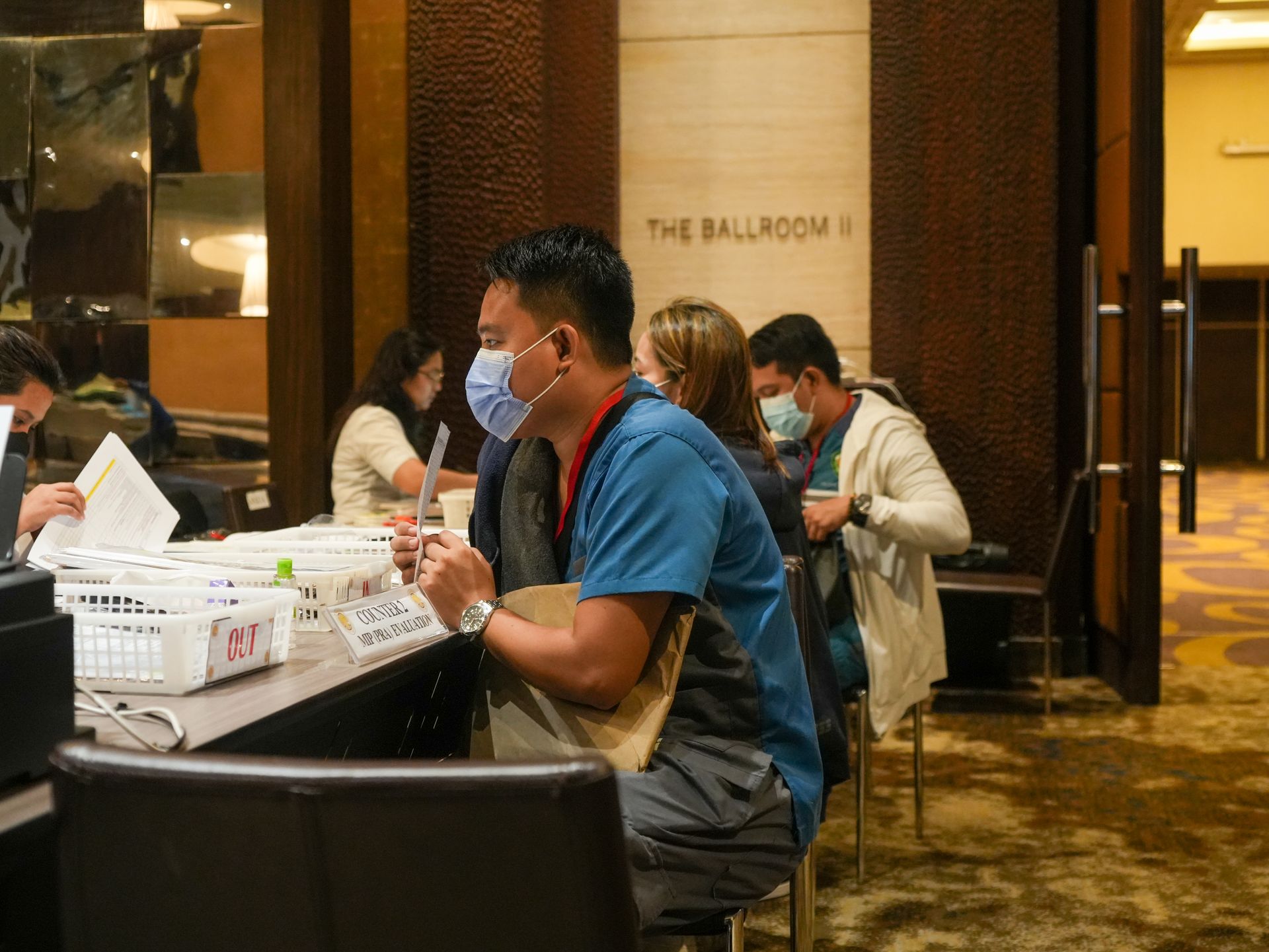 A group of people wearing face masks are sitting at a table.