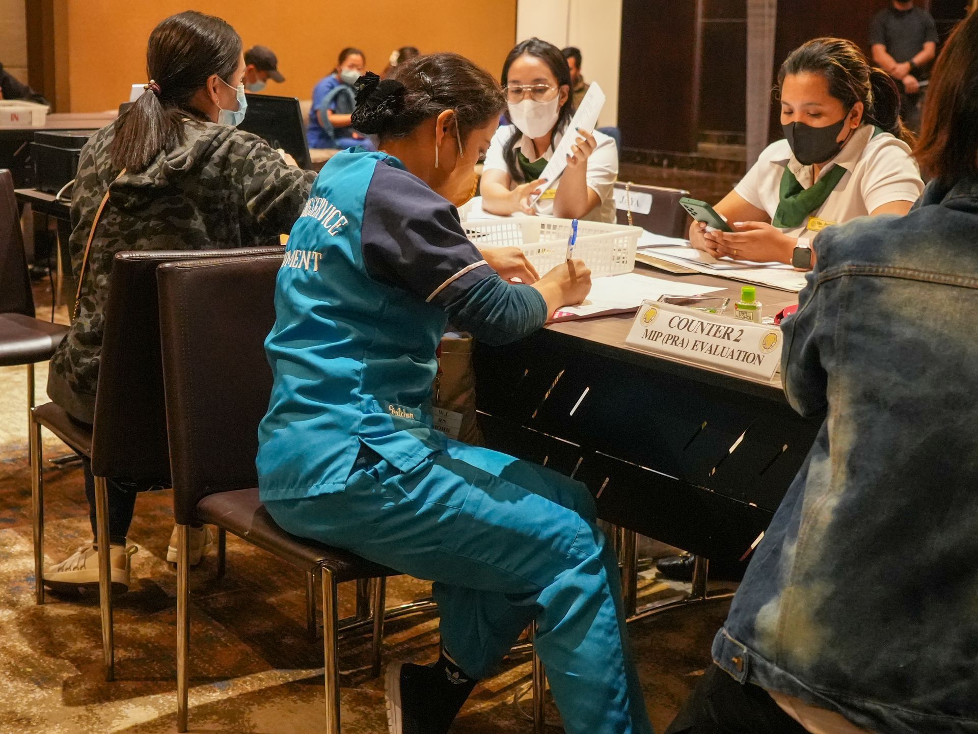 A group of people wearing masks are sitting at a table.
