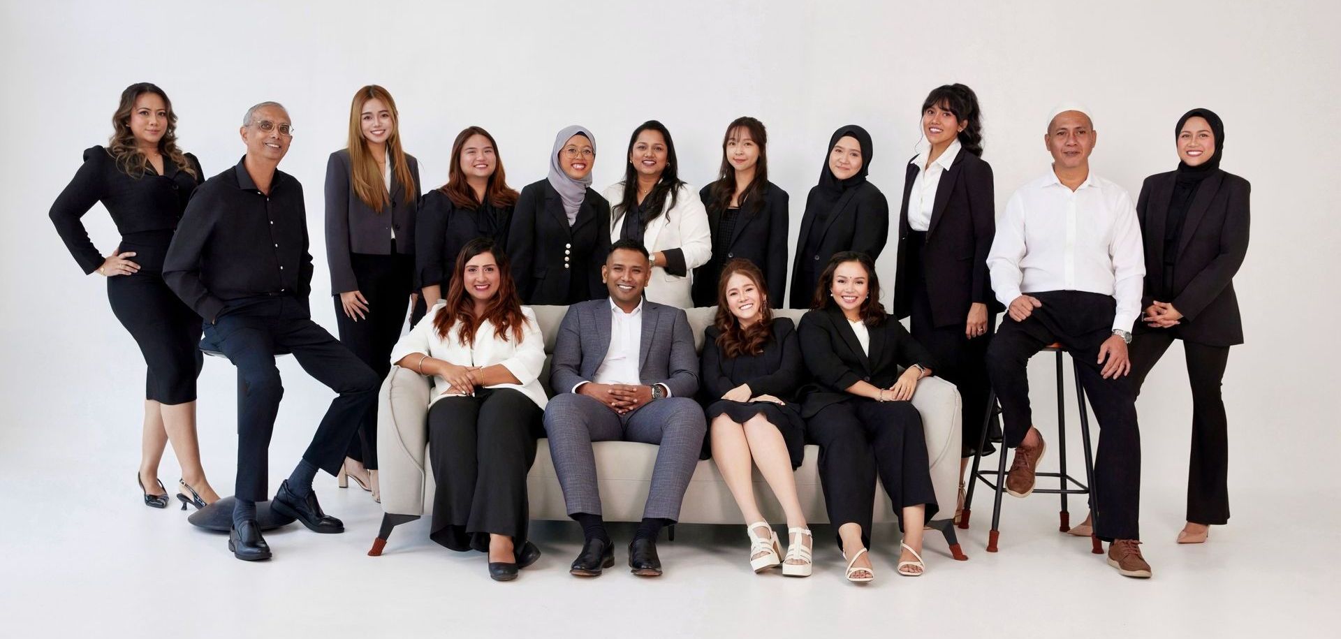 A group of people are posing for a picture while sitting on a couch.