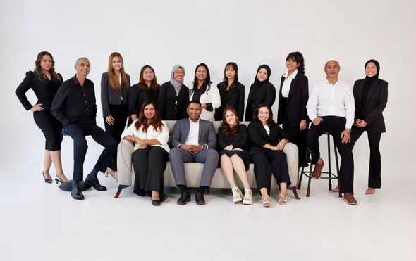 A group of people are posing for a picture while sitting on a couch.