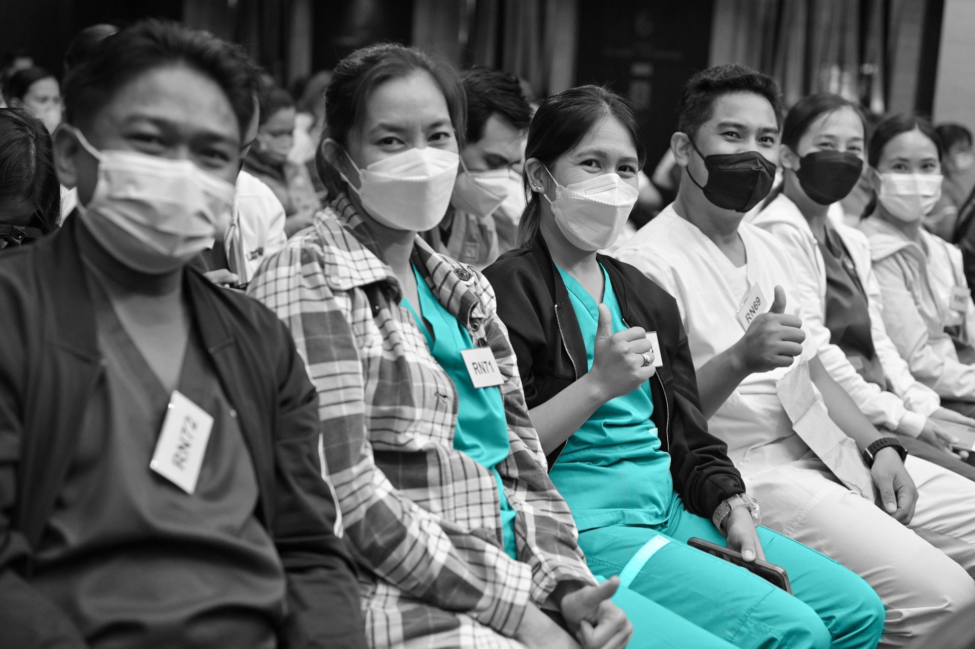 A group of people wearing face masks are sitting in a row.