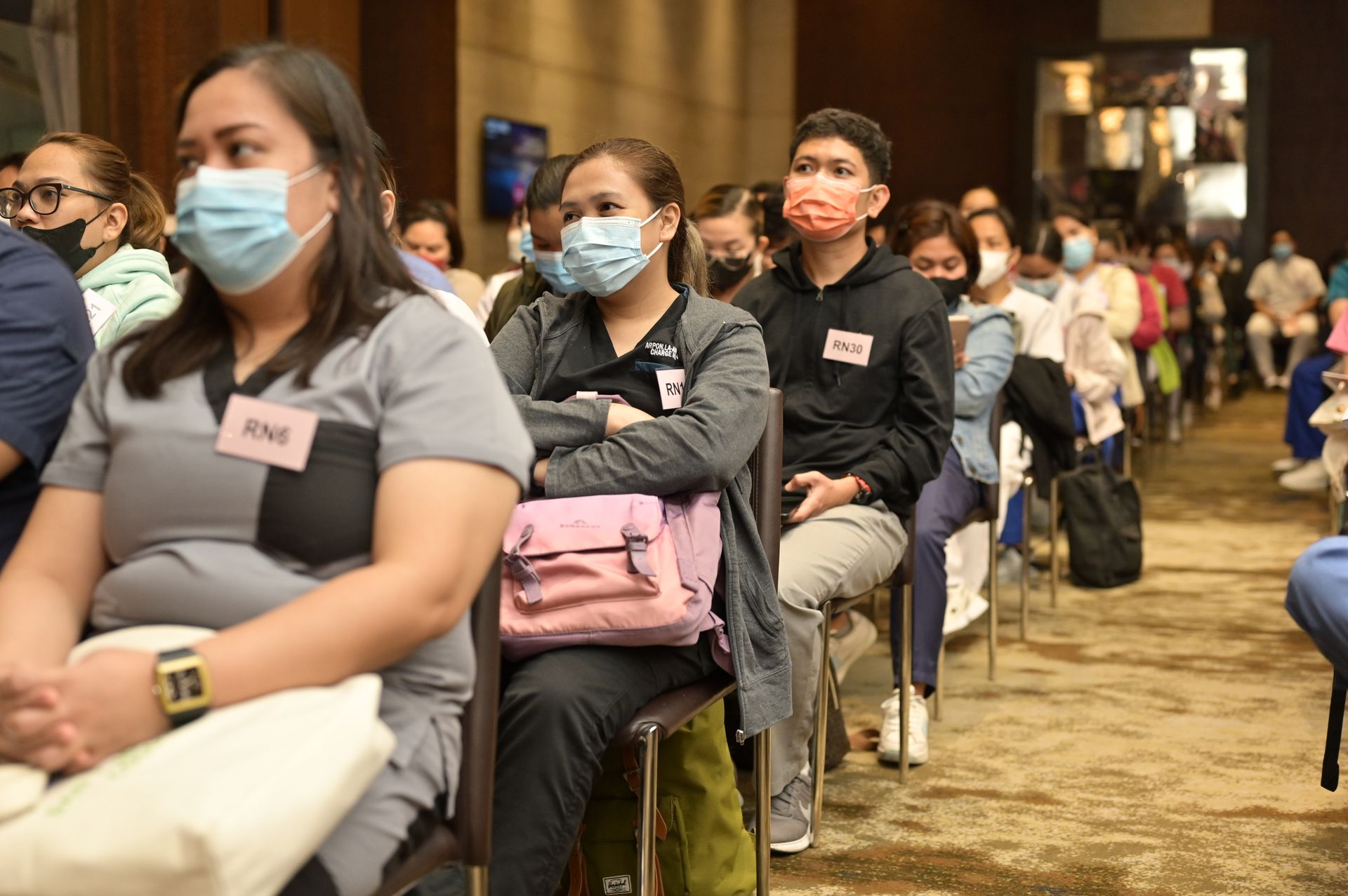 A group of people wearing face masks are sitting in chairs.