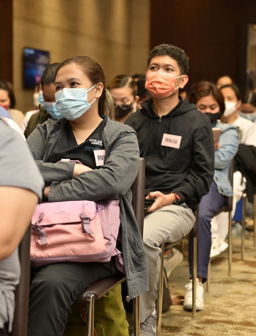 A group of people wearing face masks are sitting in chairs.