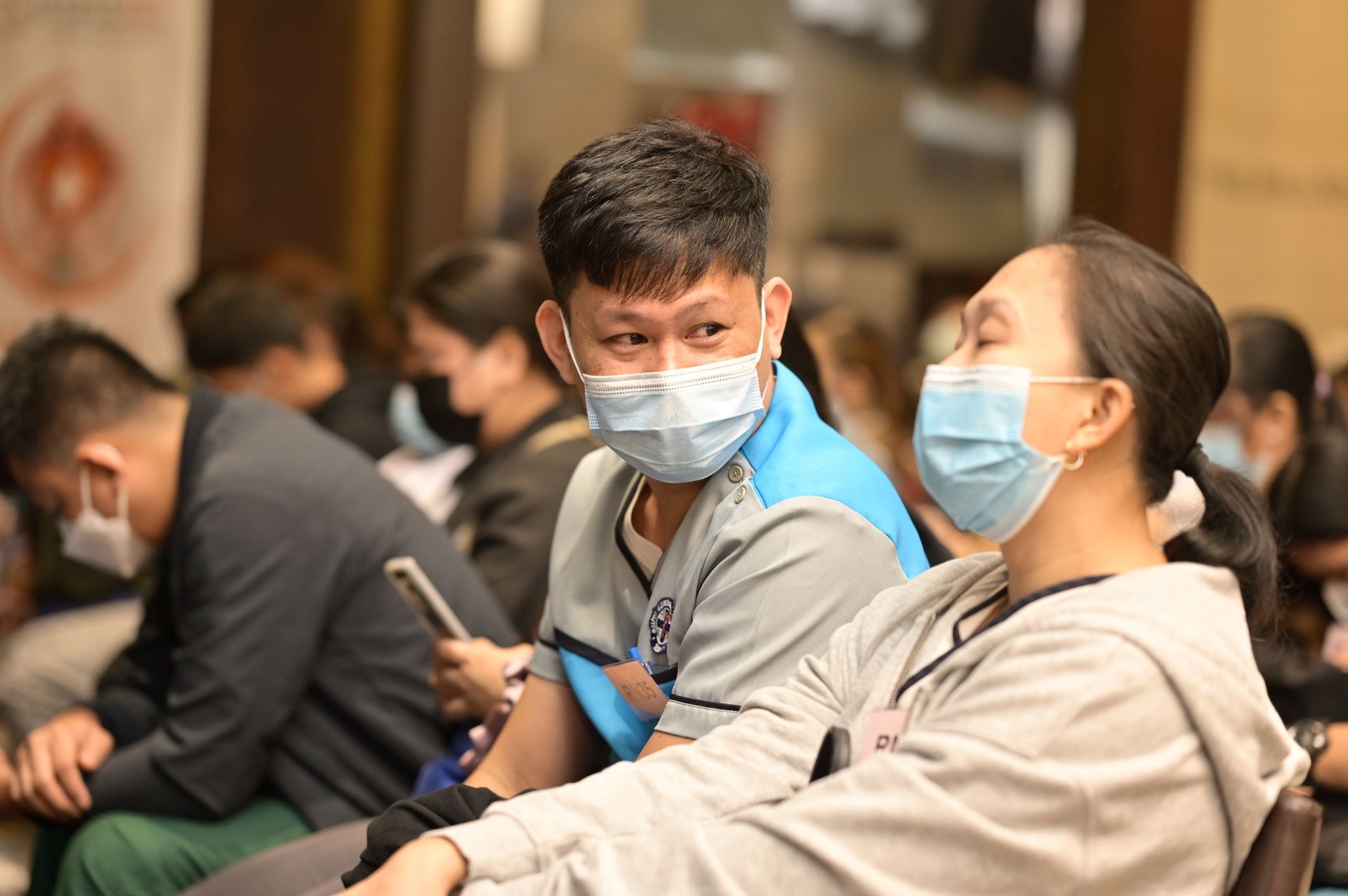 A group of people wearing face masks are sitting in a room.