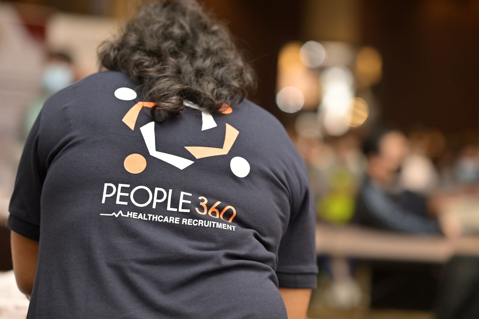 The back of a person wearing a people 360 shirt.