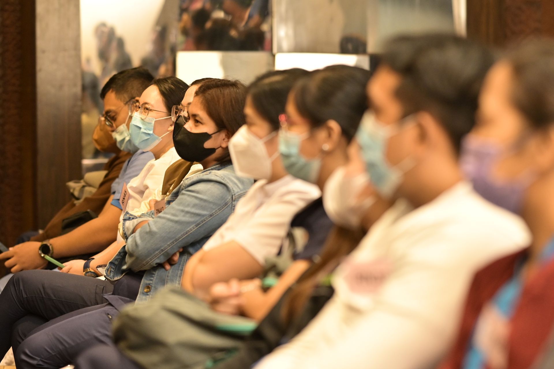 A group of people wearing face masks are sitting in a row.