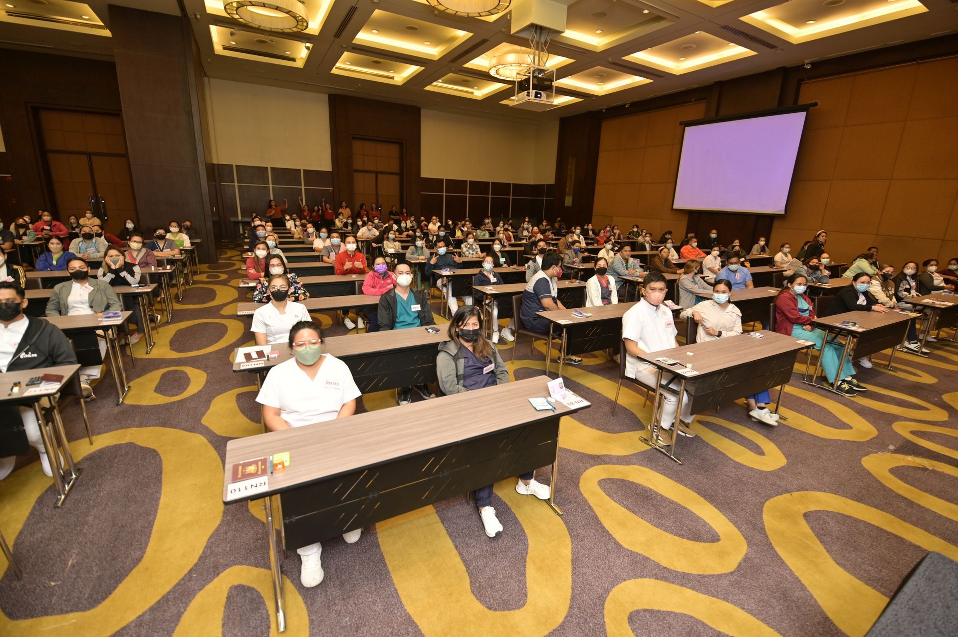 A large group of people are sitting at tables in a large room.
