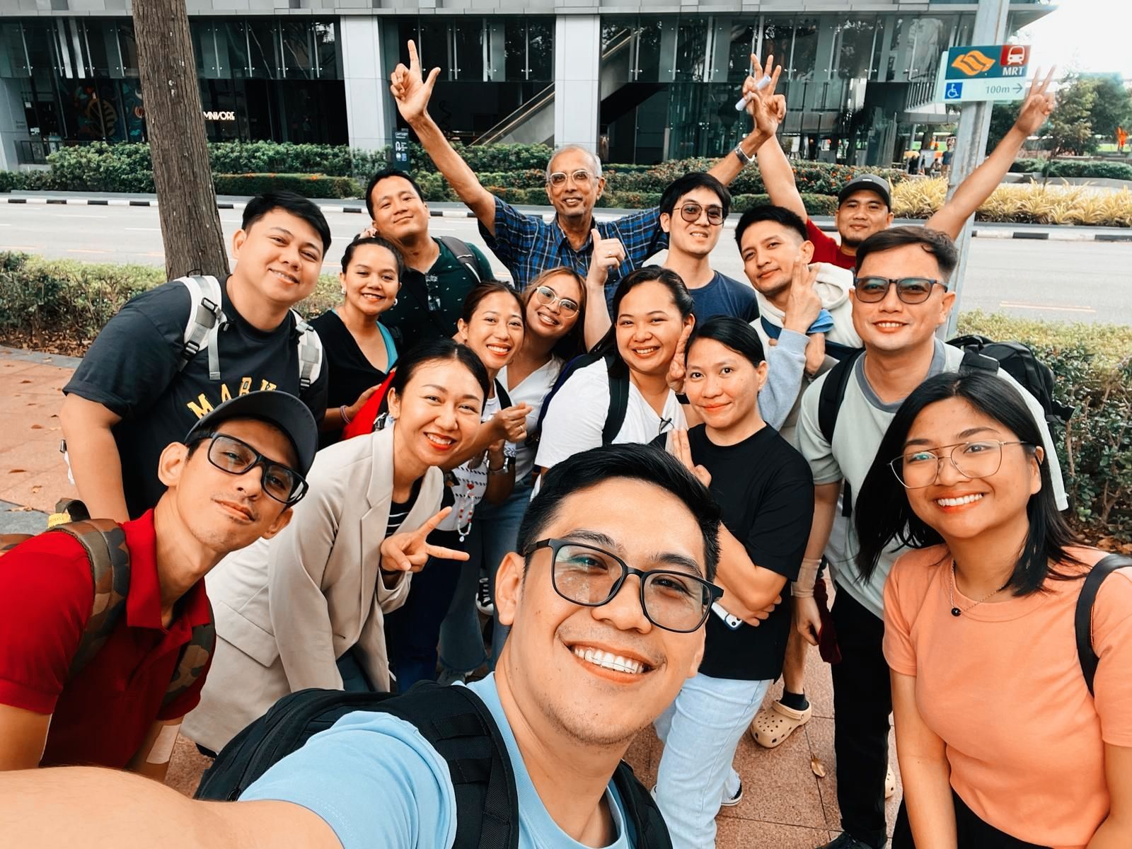 A group of people are posing for a selfie in front of a building.