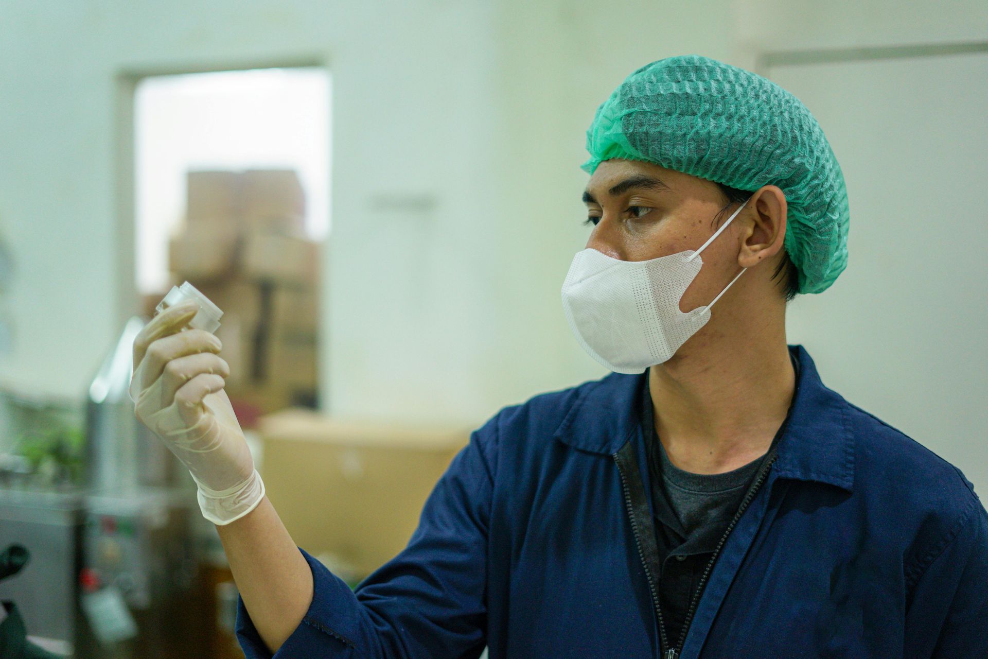A man wearing a mask and gloves is holding a bottle.