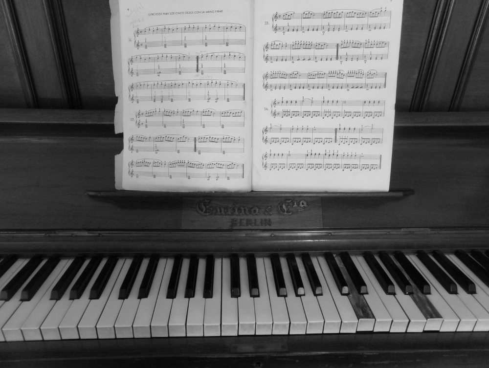 A black and white photo of a piano with sheet music on it