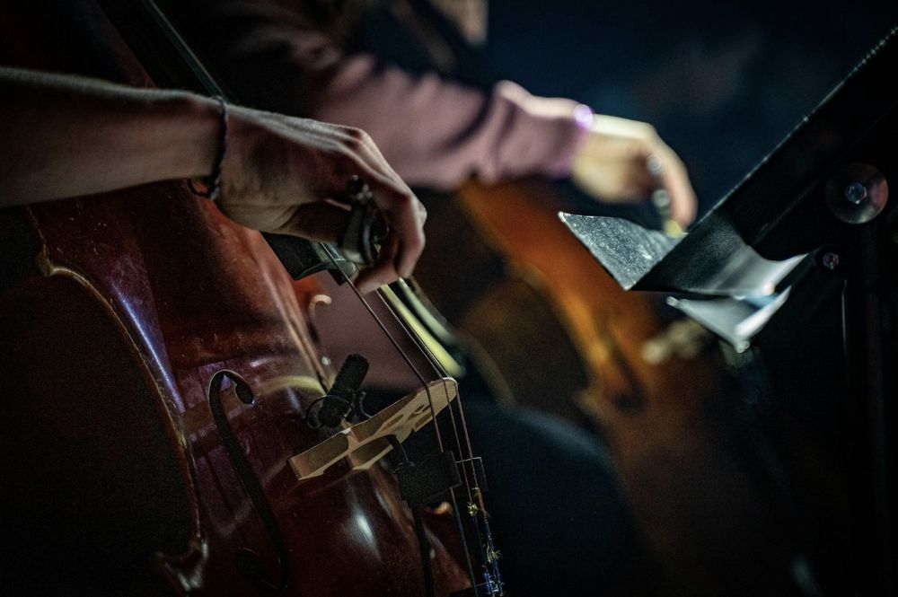 A person is playing a cello in a dark room.