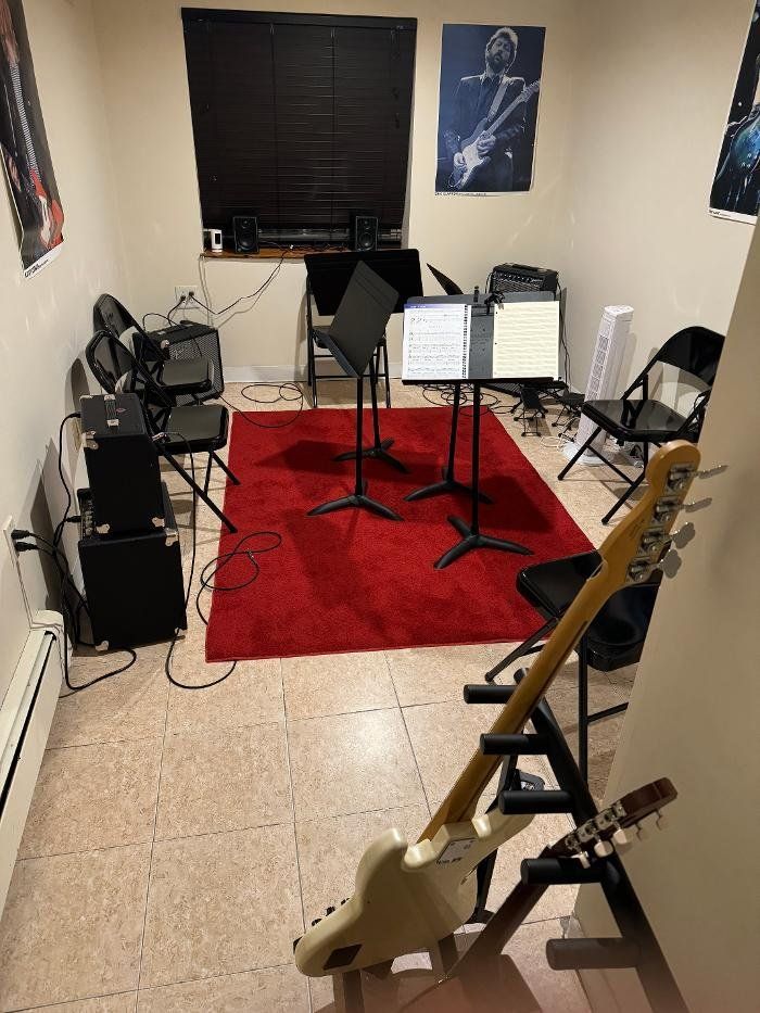 A guitar is sitting on a stand in a room with a red rug.
