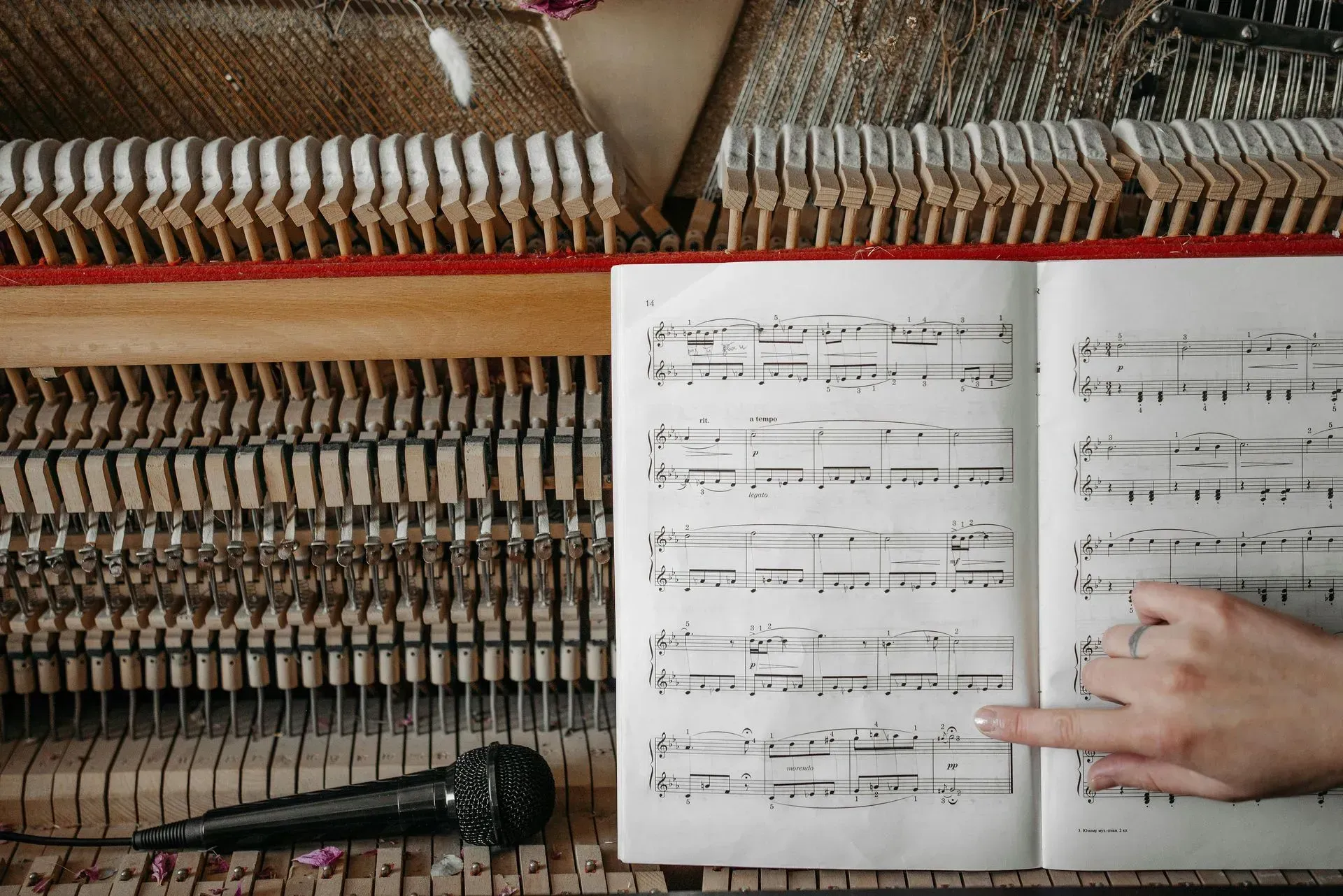 A person is pointing at a sheet of music on a piano.