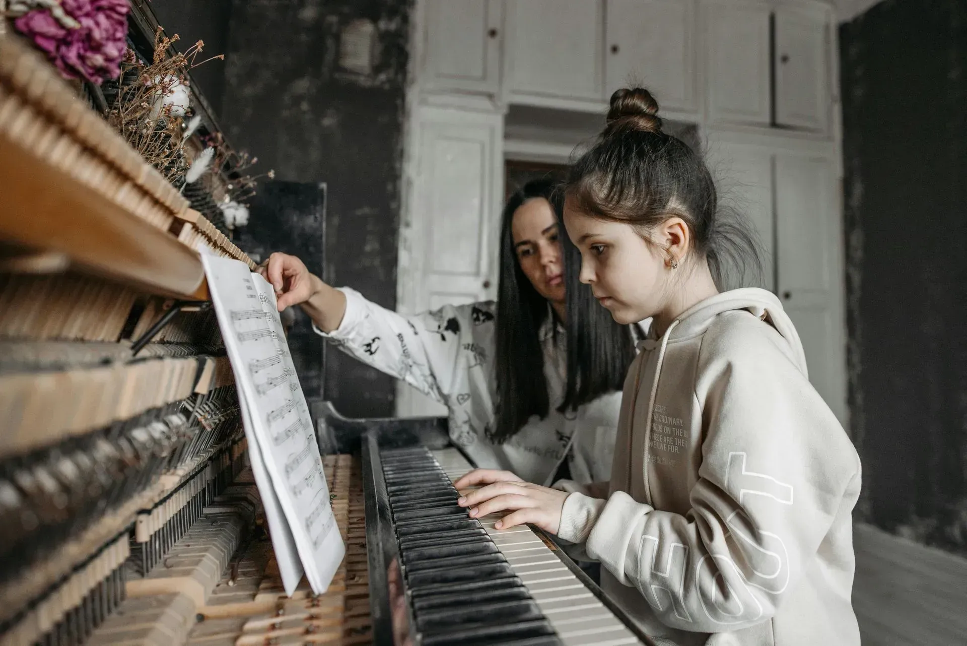 A woman is teaching a little girl how to play the piano.