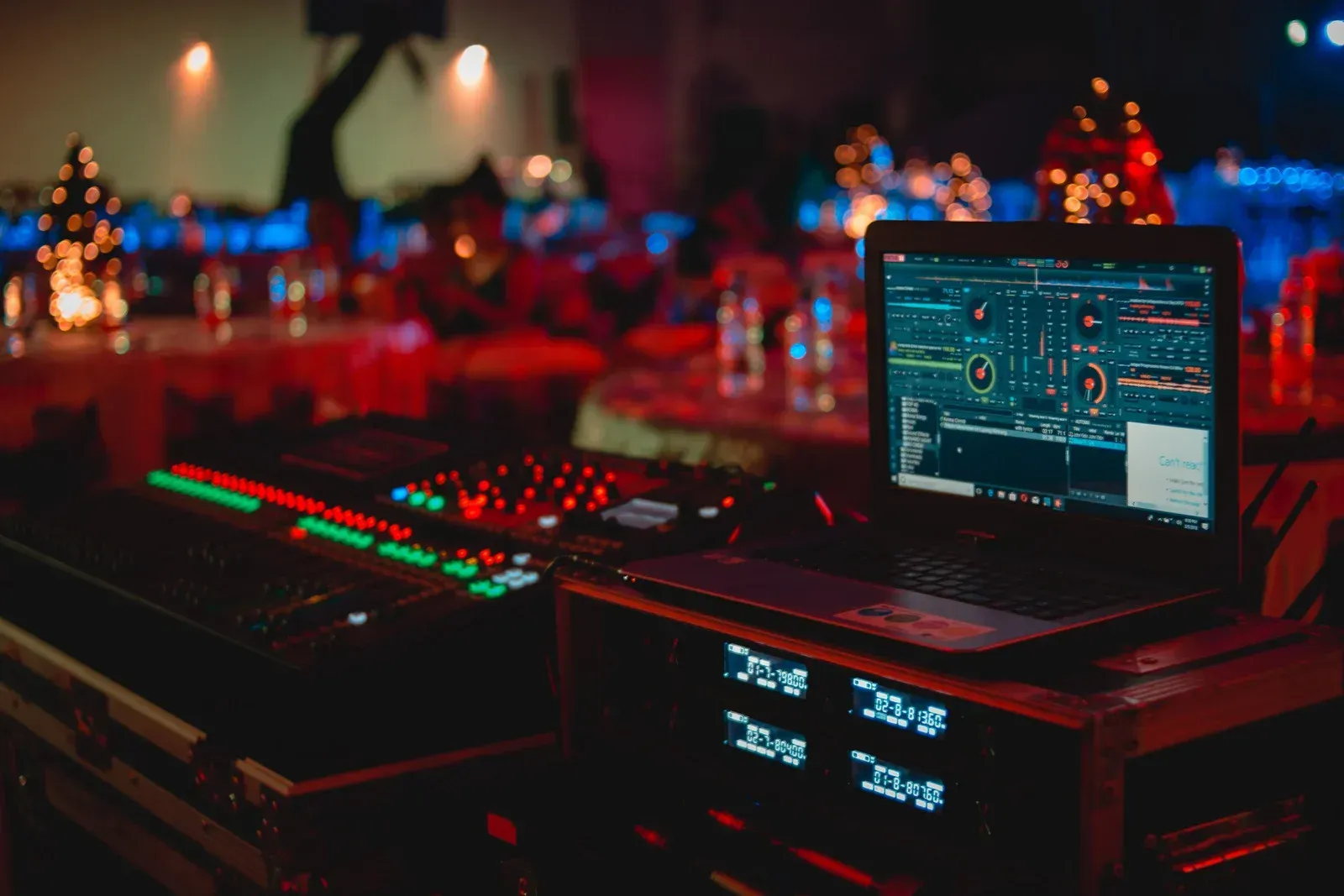 A laptop is sitting on top of a mixer in a dark room.
