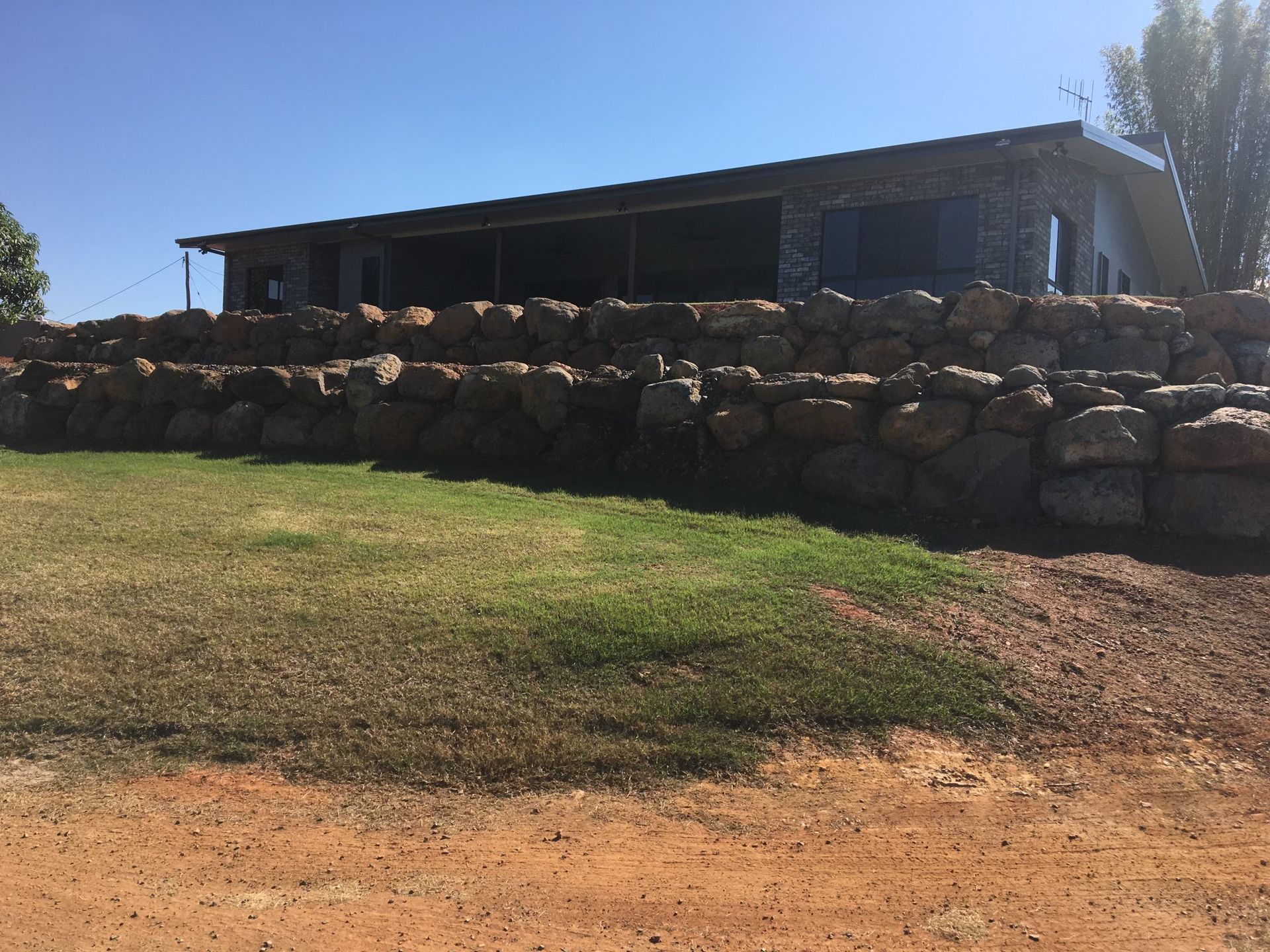 A Stone Retaining Wall in Front of A Building — A1 Rock This City Truck & Dog Hire In Good Night, QLD
