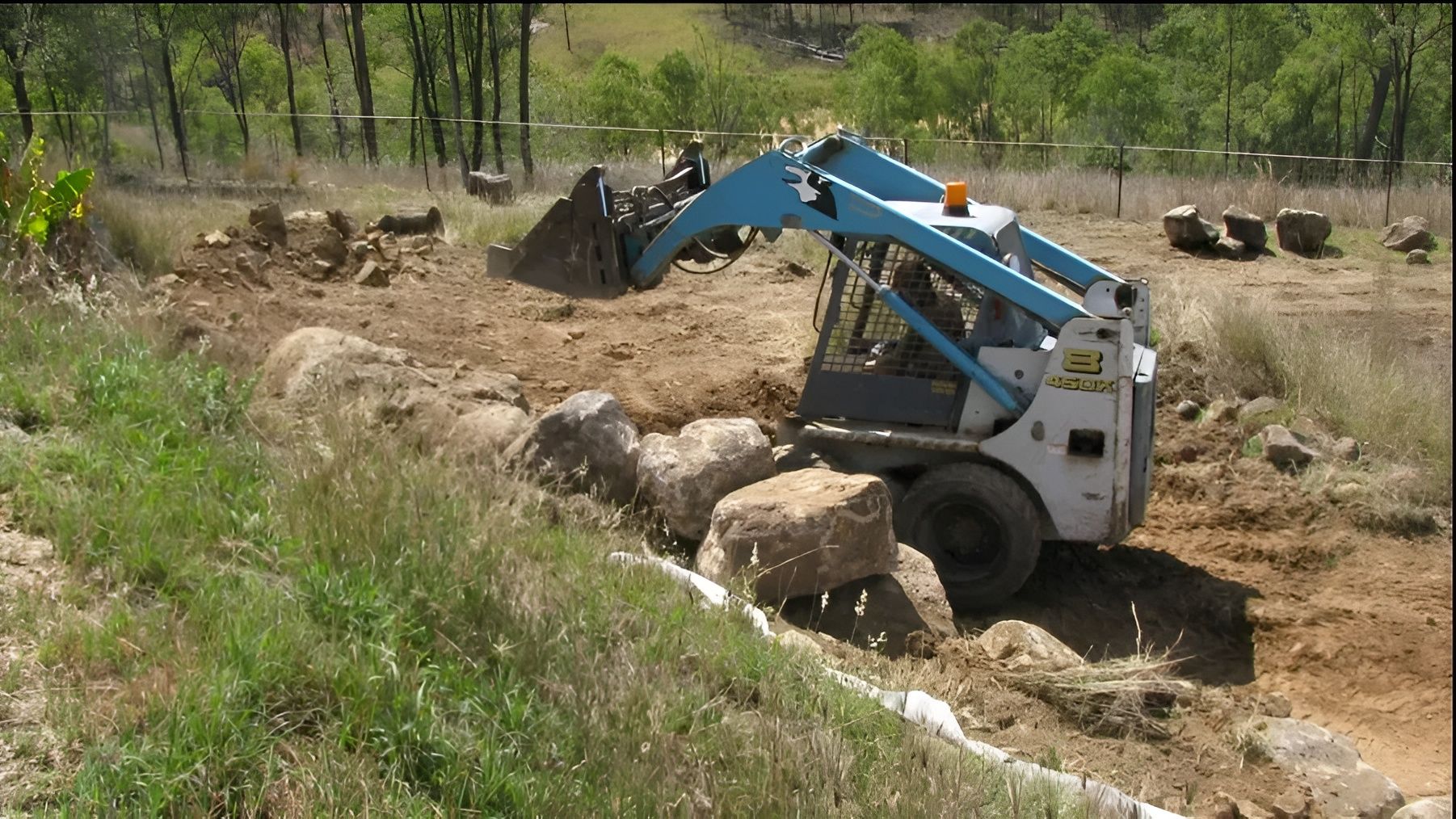 Blue and White Skid Steer Loader Moving Rocks and Dirt in A Field — A1 Rock This City Truck & Dog Hire In Good Night, QLD