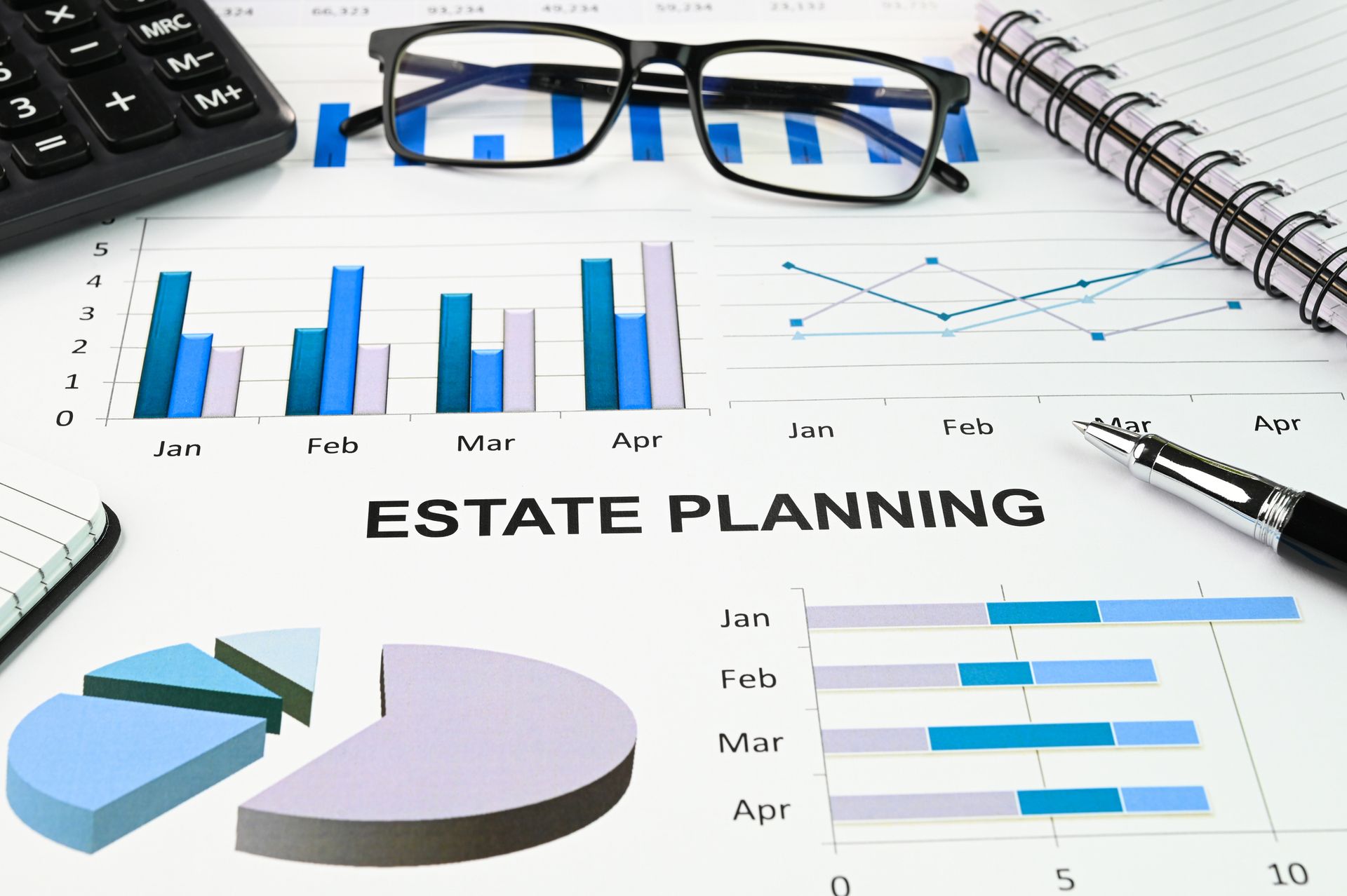 Estate planning documents with charts, graphs, calculator, glasses, pen, and notepad.