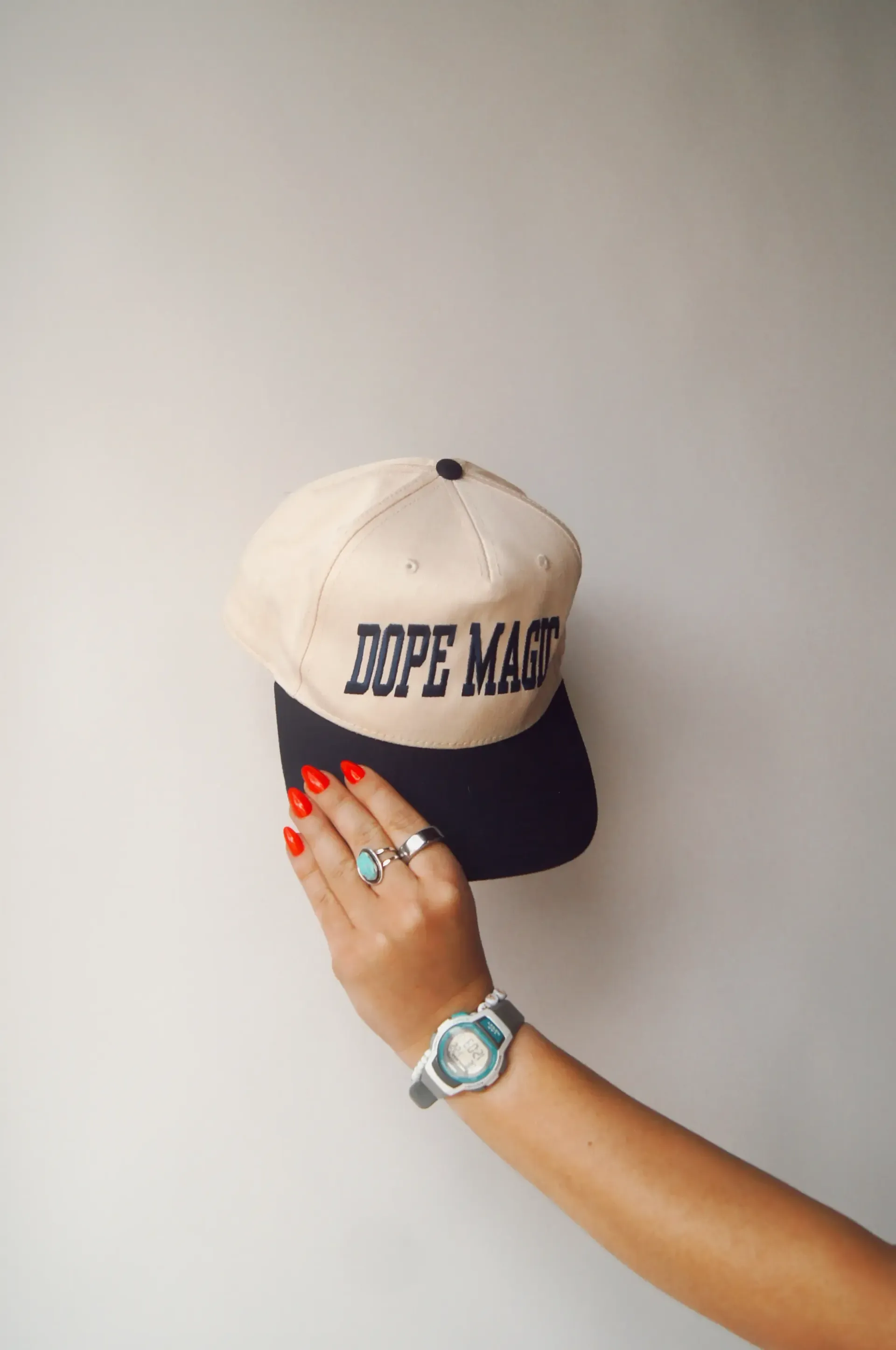 A person’s hand holds up a beige and black baseball cap with