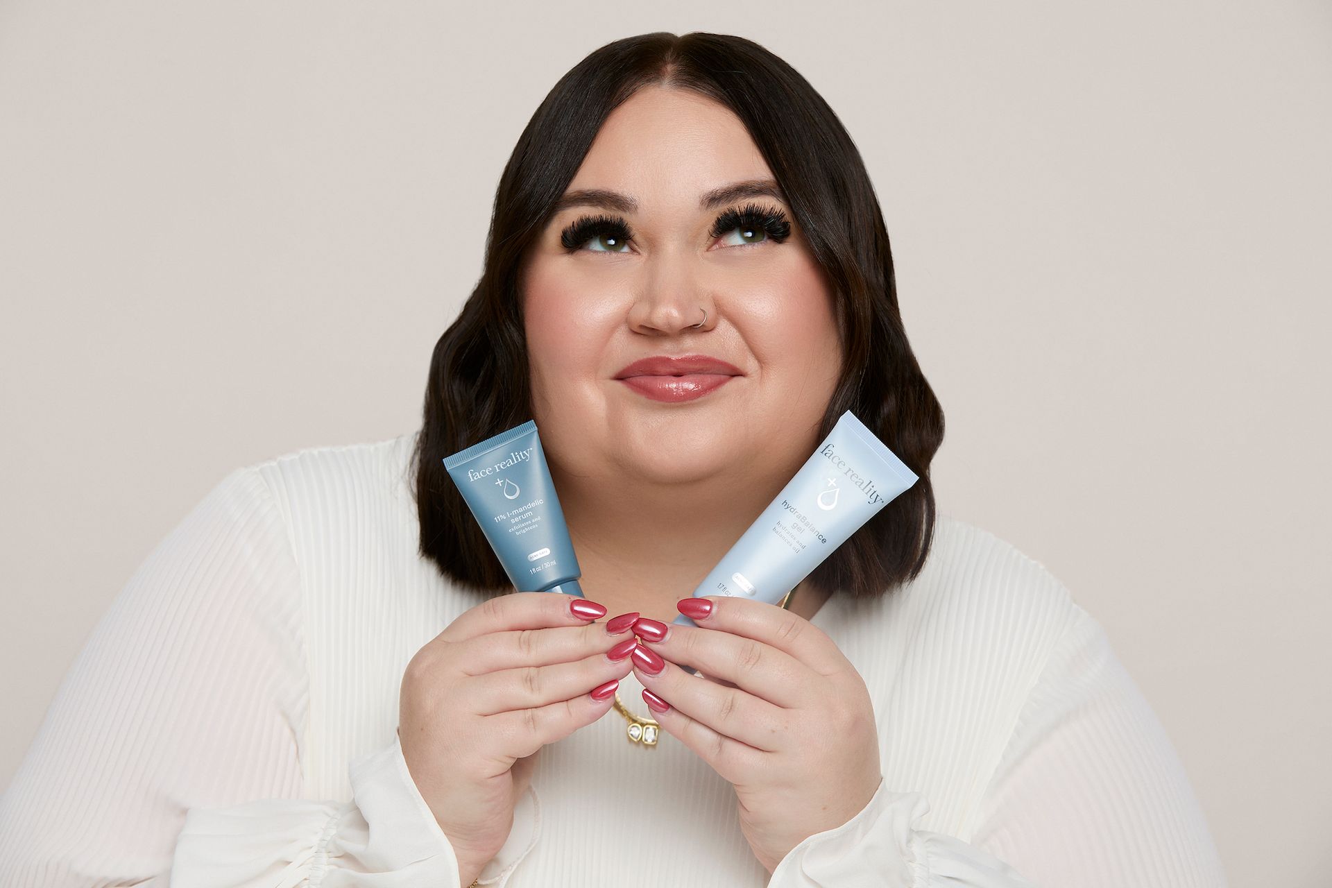 Woman holding two blue tubes, looking upward, smiling.
