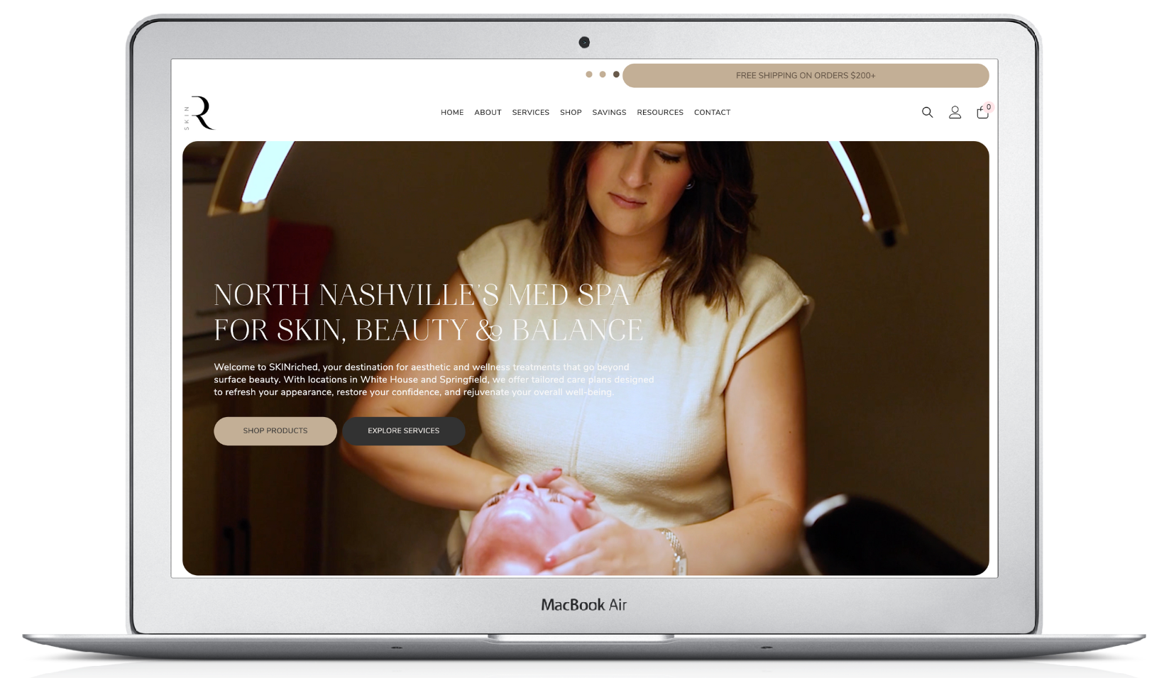 A woman performing a facial treatment in a beauty clinic; website homepage on a laptop.
