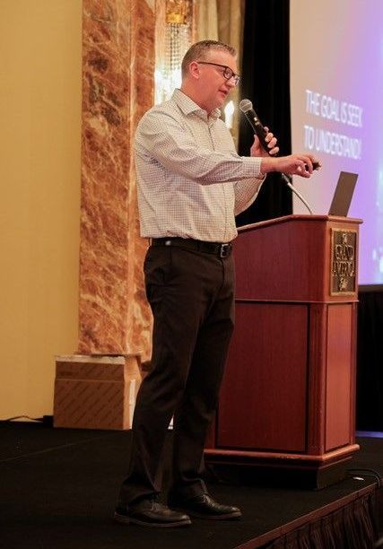 A man is standing at a podium giving a presentation.