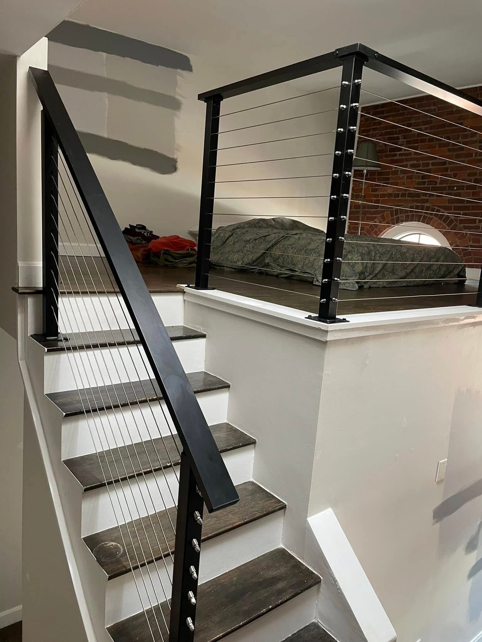 Staircase with black metal railing and perforated metal panels leading up to a loft area.