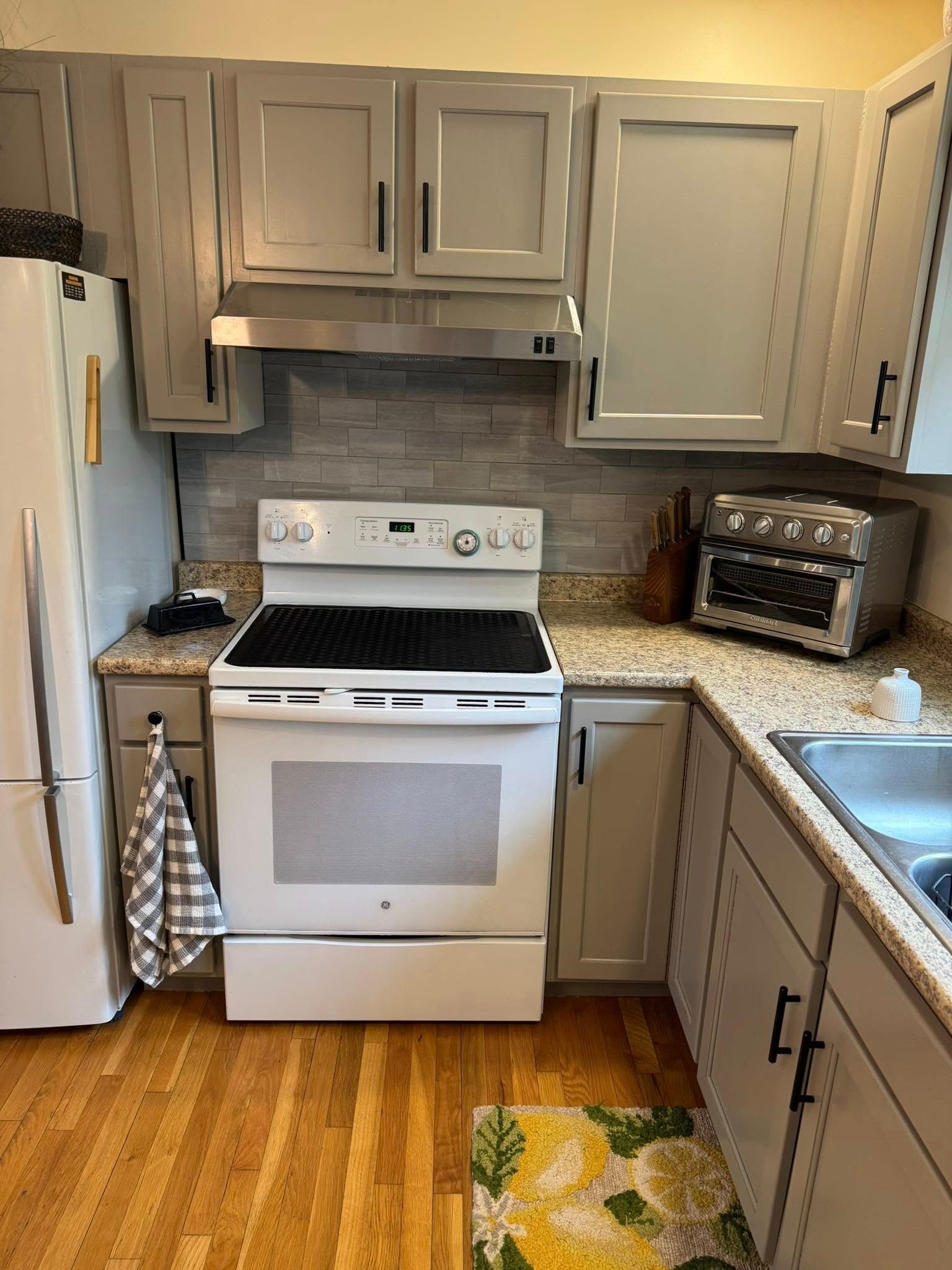 Kitchen with gray cabinets, white appliances, and light wood floors.