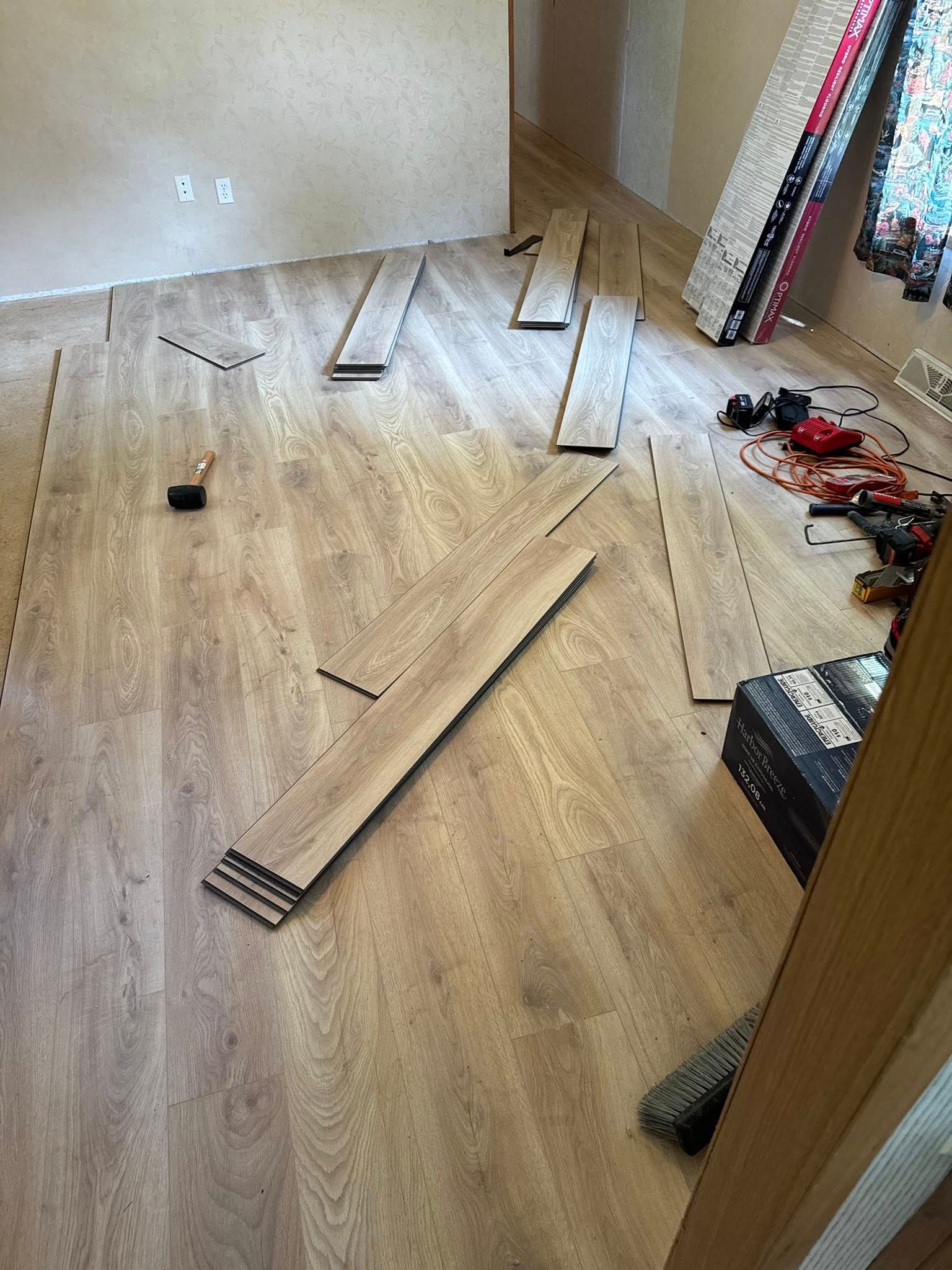Herringbone wood flooring installation in progress, light brown planks on a light brown floor.
