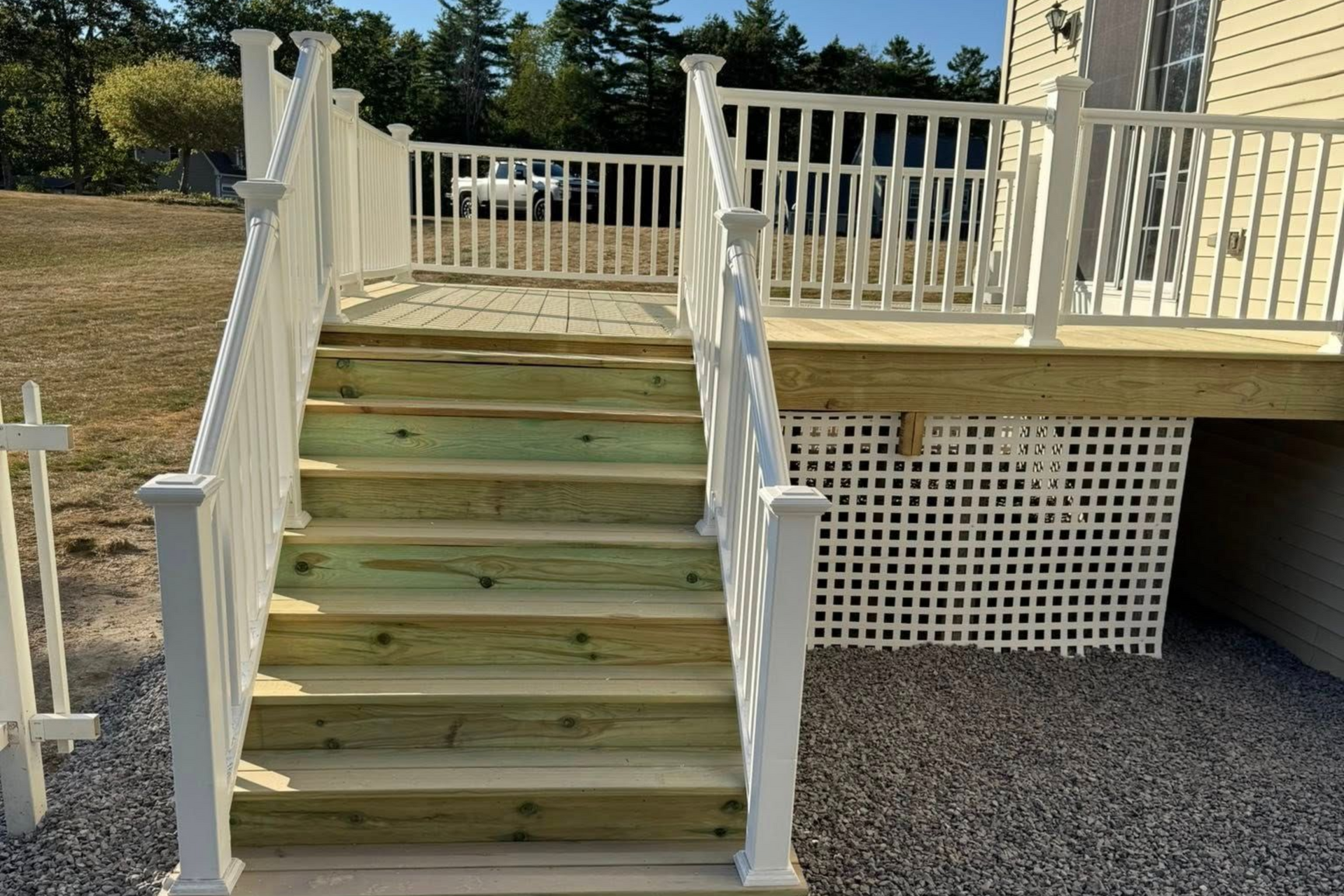 White deck and stairs with green wooden steps, in an outdoor setting.