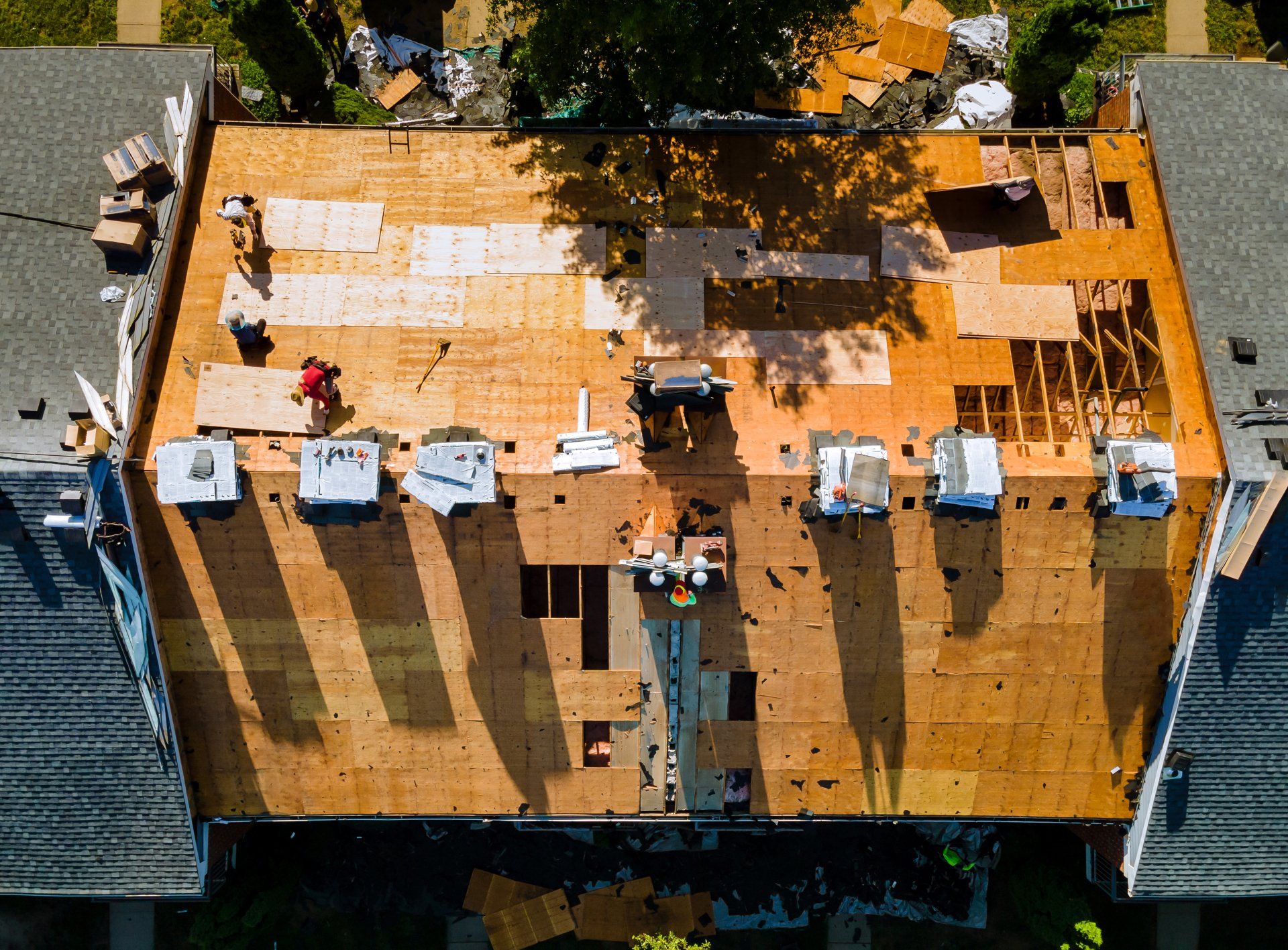 Vue aérienne d'un toit en réparation. Un ouvrier travaille sur un toit partiellement recouvert