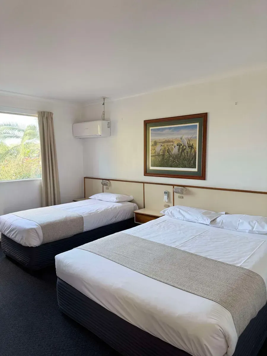 Two Beds in a Cozy Room With a Colorful Painting Hanging on the Wall Above Them — Country Comfort Gin Gin Wild Scotsman Motor Inn in Gin Gin, QLD