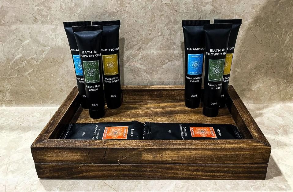 A Wooden Tray With Bottles of Lotion on It — Country Comfort Gin Gin Wild Scotsman Motor Inn in Gin Gin, QLD