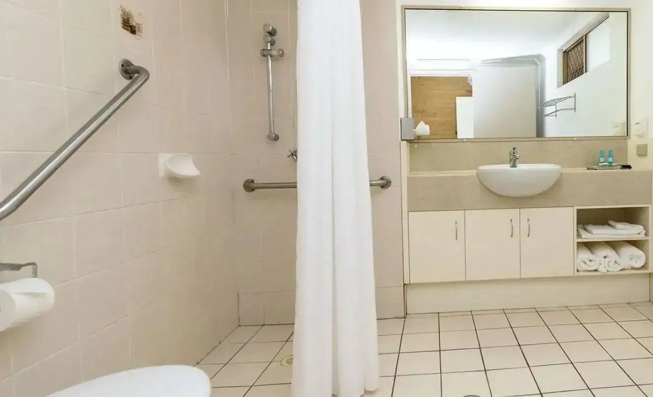 A Bathroom With a Toilet a Sink and a Shower Curtain — Country Comfort Gin Gin Wild Scotsman Motor Inn in Gin Gin, QLD