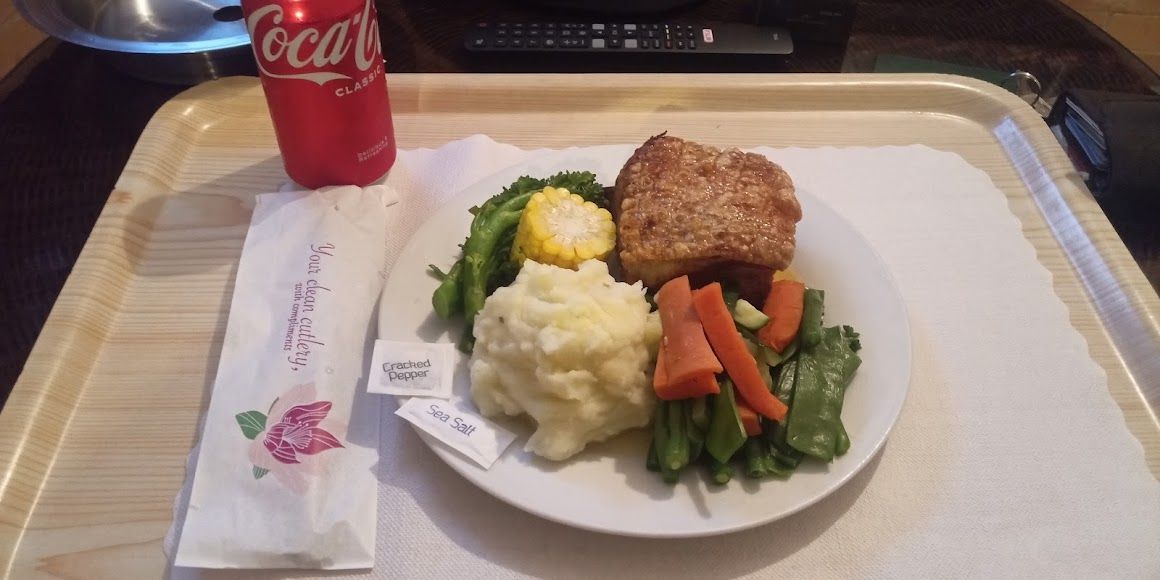 A Plate of Food and a Can of Coca Cola on a Tray — Country Comfort Gin Gin Wild Scotsman Motor Inn in Gin Gin, QLD