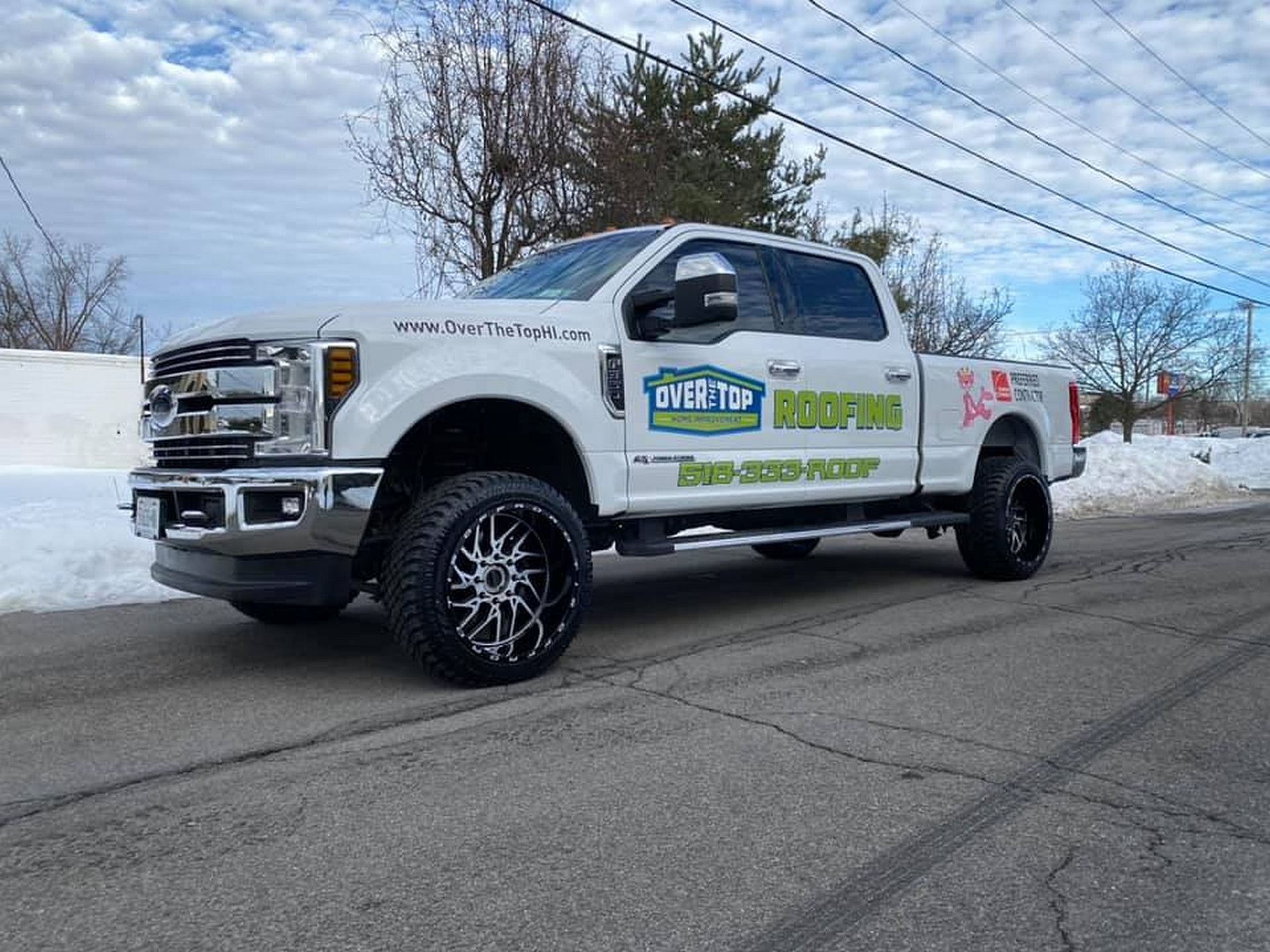 A white truck is parked on the side of the road in the snow.