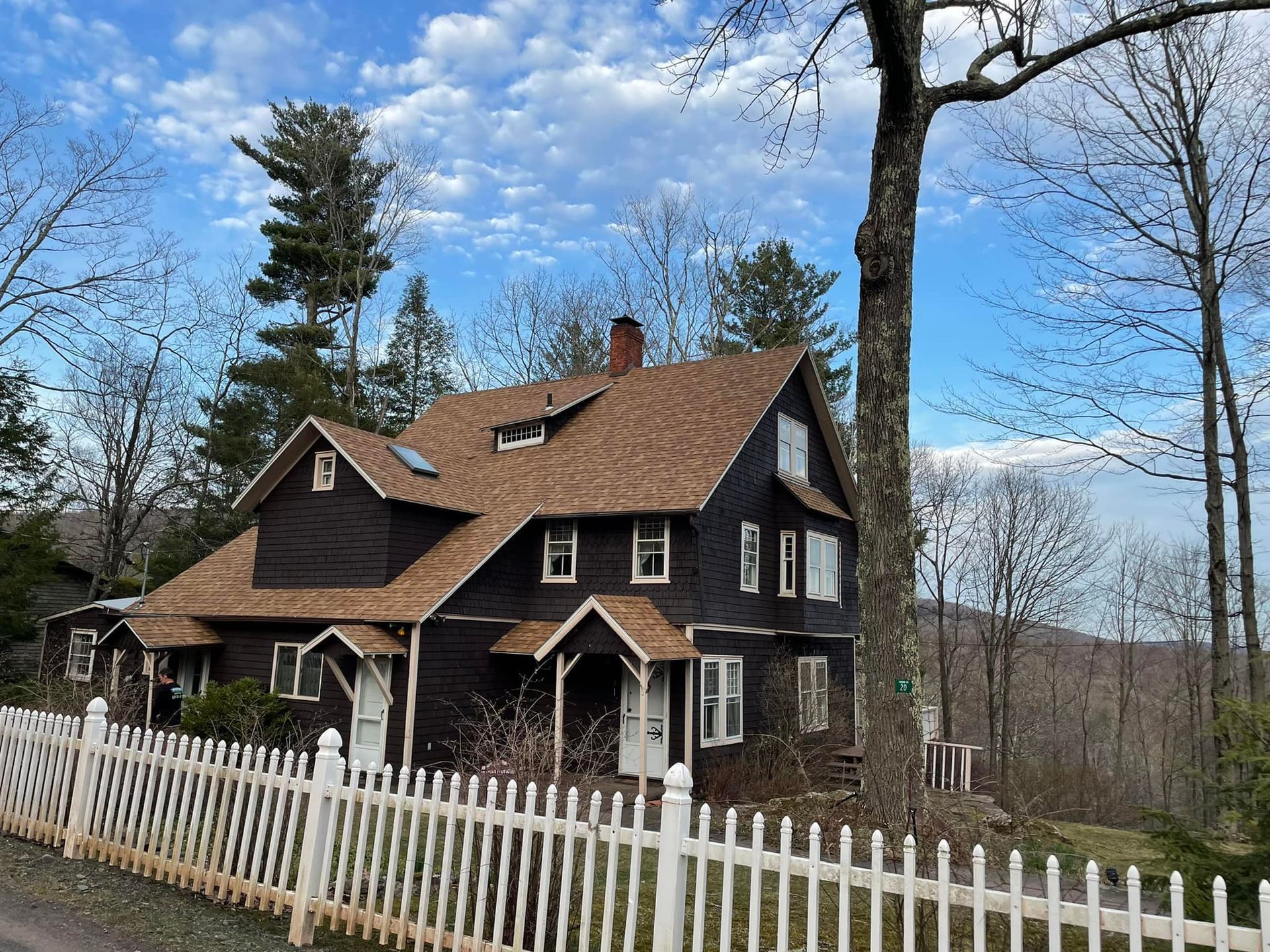 A black house with a brown roof and a white picket fence